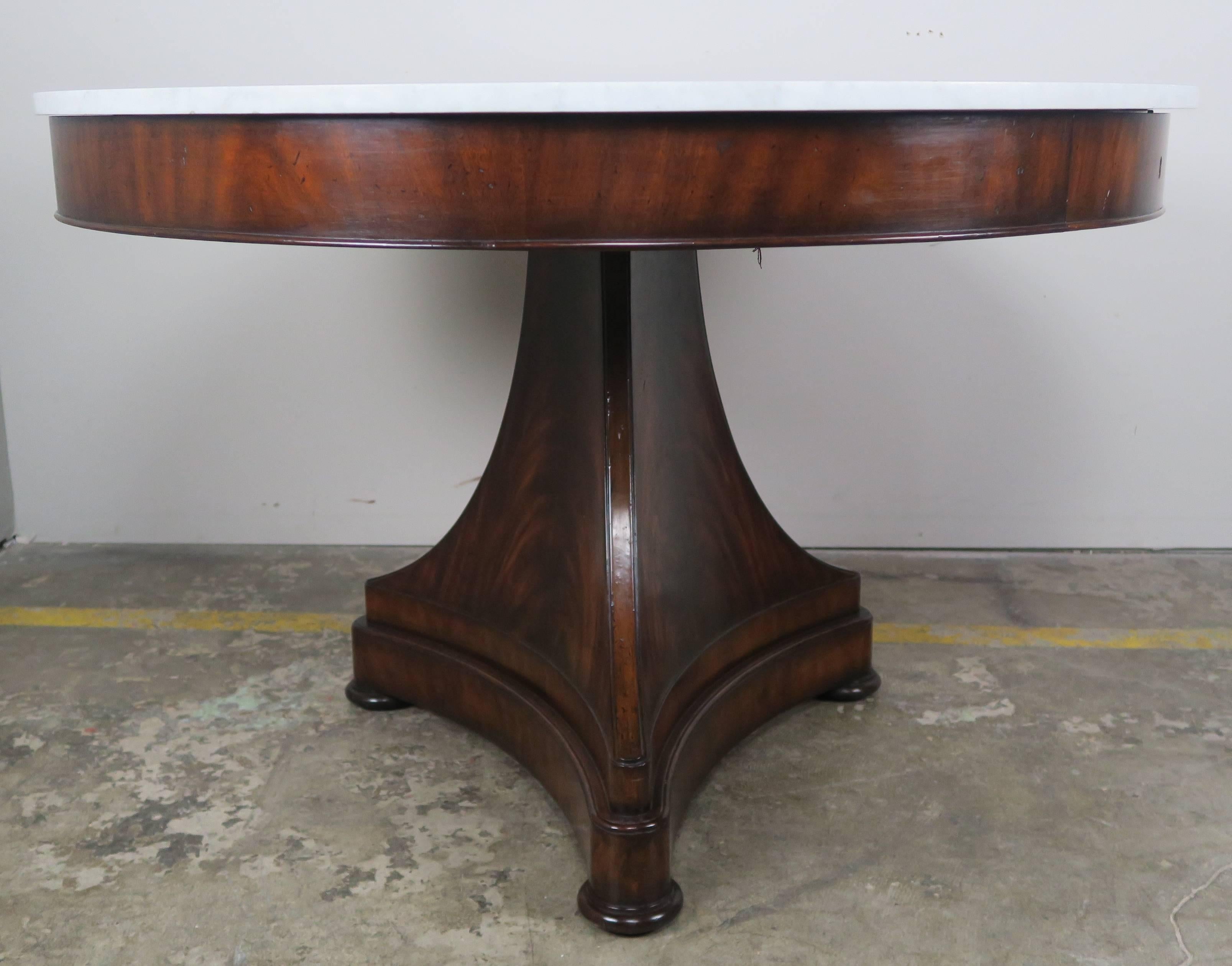 Ralph Lauren flamed mahogany centre table with white marble top. The table sits on a single pedestal base that stands on three bun feet. Two drawers on opposite ends of table.