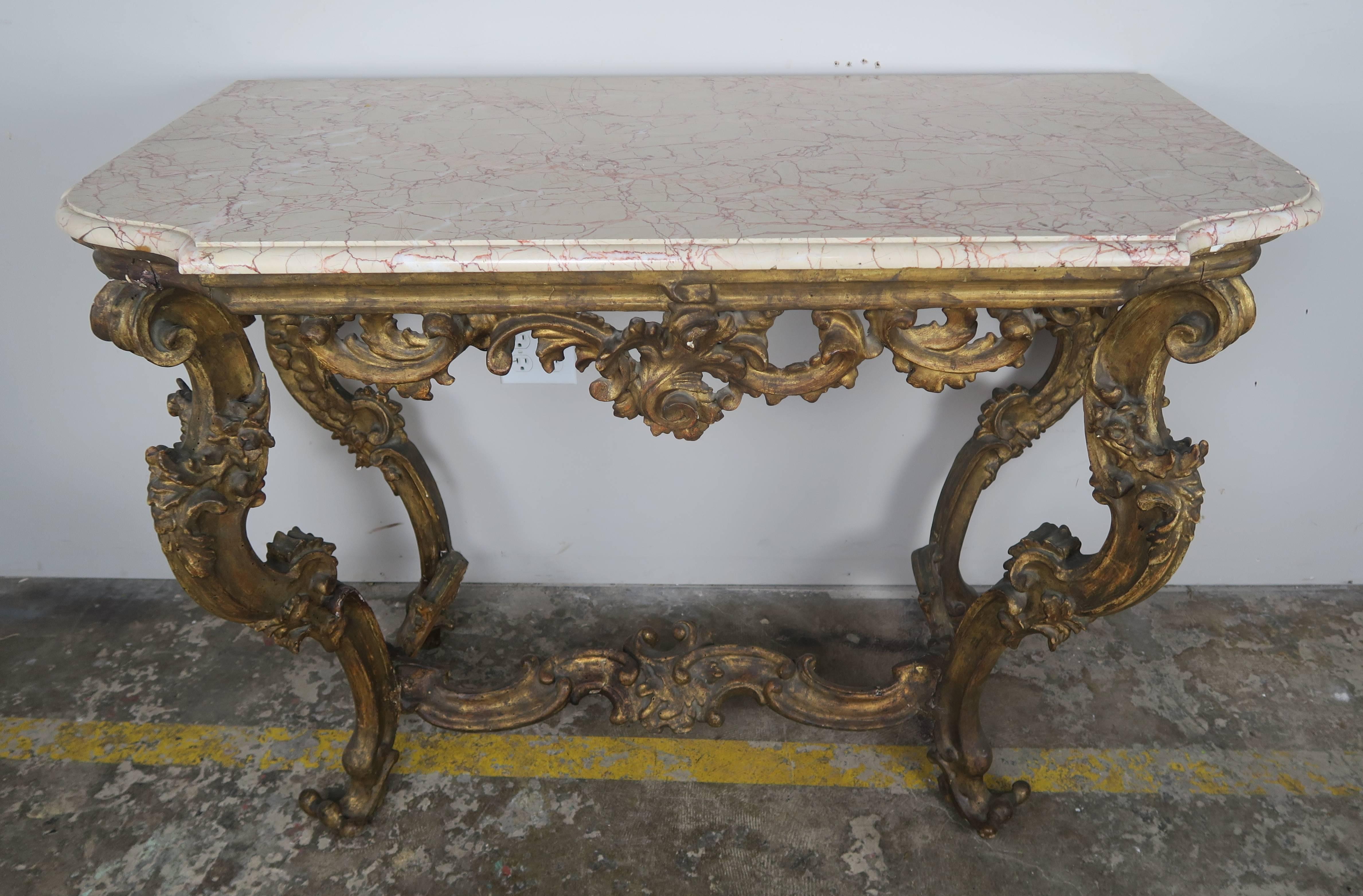 19th century Italian Rococo style giltwood carved console with marble top with a single ogee edge detail. The console is beautifully carved and adorned with garlands of flowers twisting around the scrolled legs and acanthus leaves swirling together