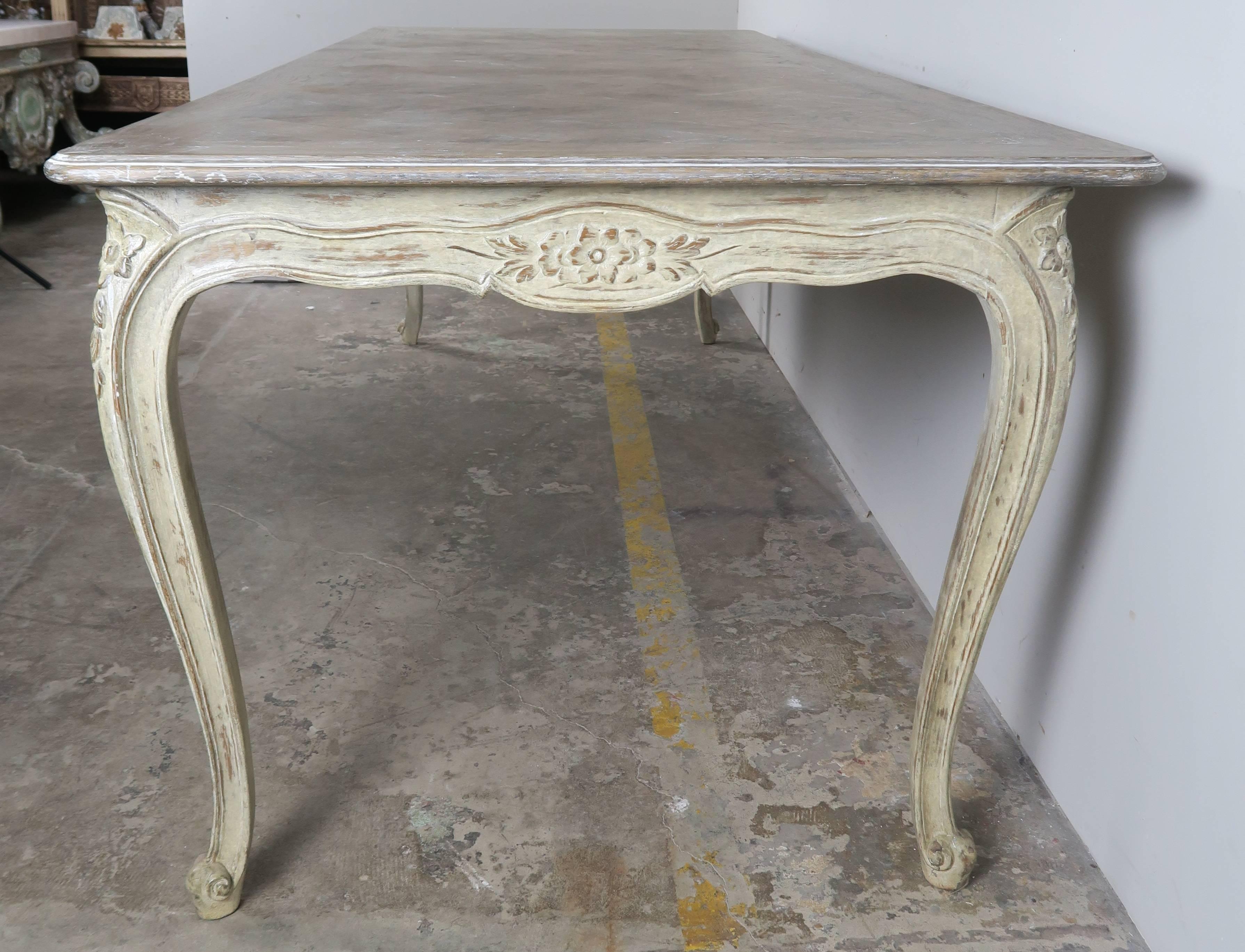 French Louis XV style painted dining table standing on four cabriole legs ending in ram's head feet. Chevron pattern inlaid top. Soft celadon colored washed painted finish.