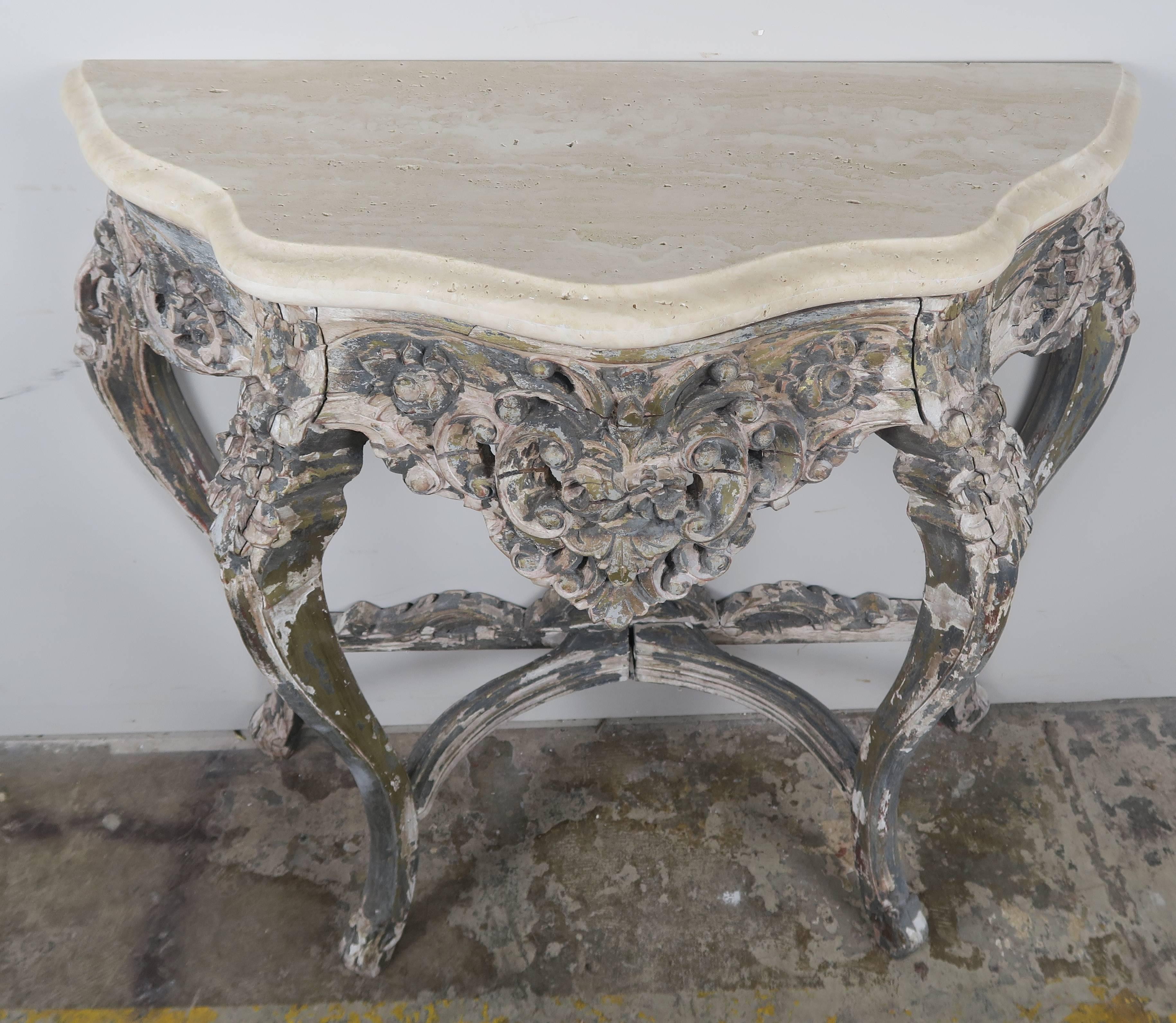 French painted carved Rococo style wood console standing on four cabriole legs that meet at centre finial. Distressed worn paint. Travertine top with an ogee-bullnose edge detail.
