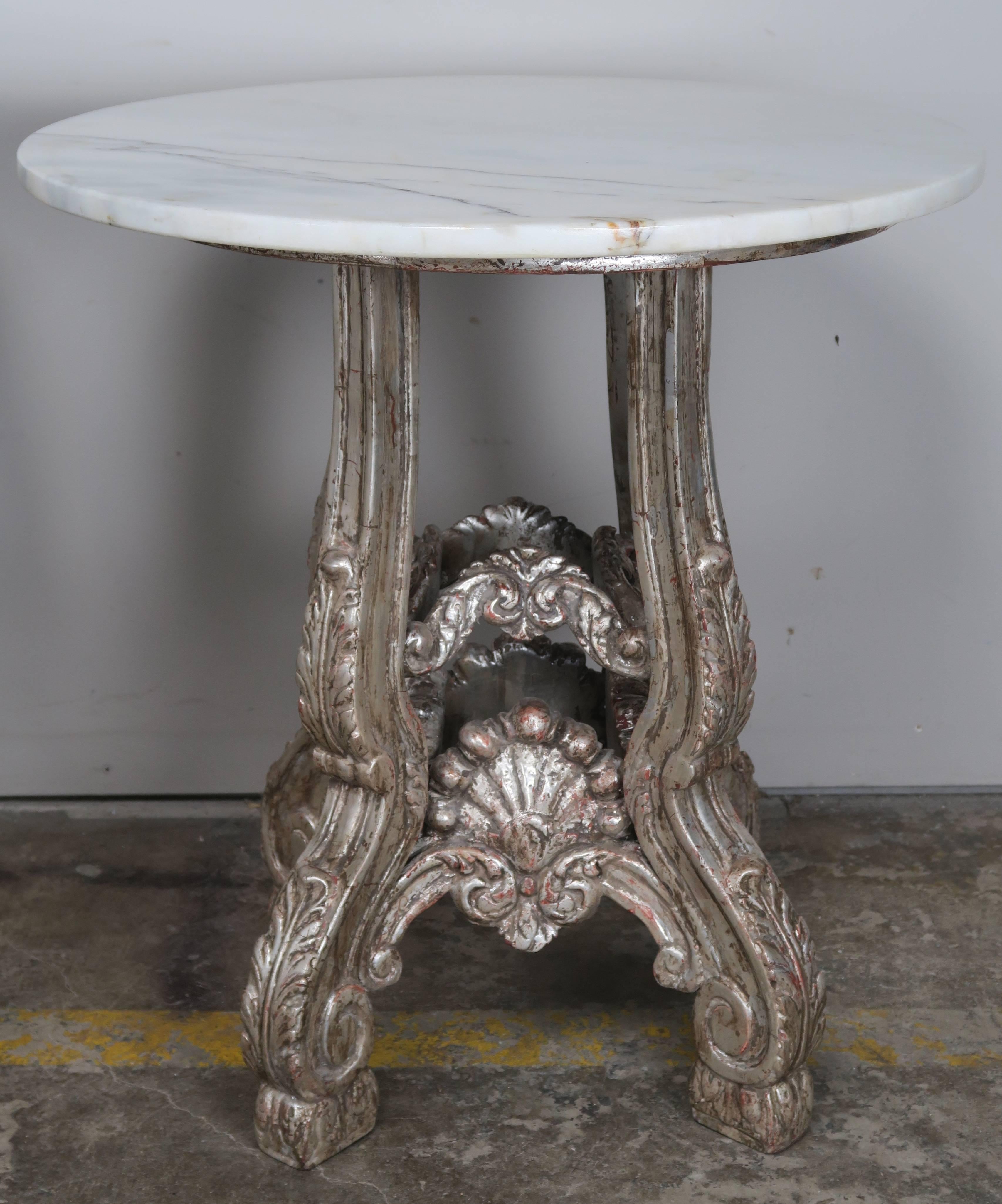 Pair of 1930s French silver leaf carved wood tables standing on four legs with acanthus leaf and scrolled details. Carved shells on all four sides. Carrara marble tops.