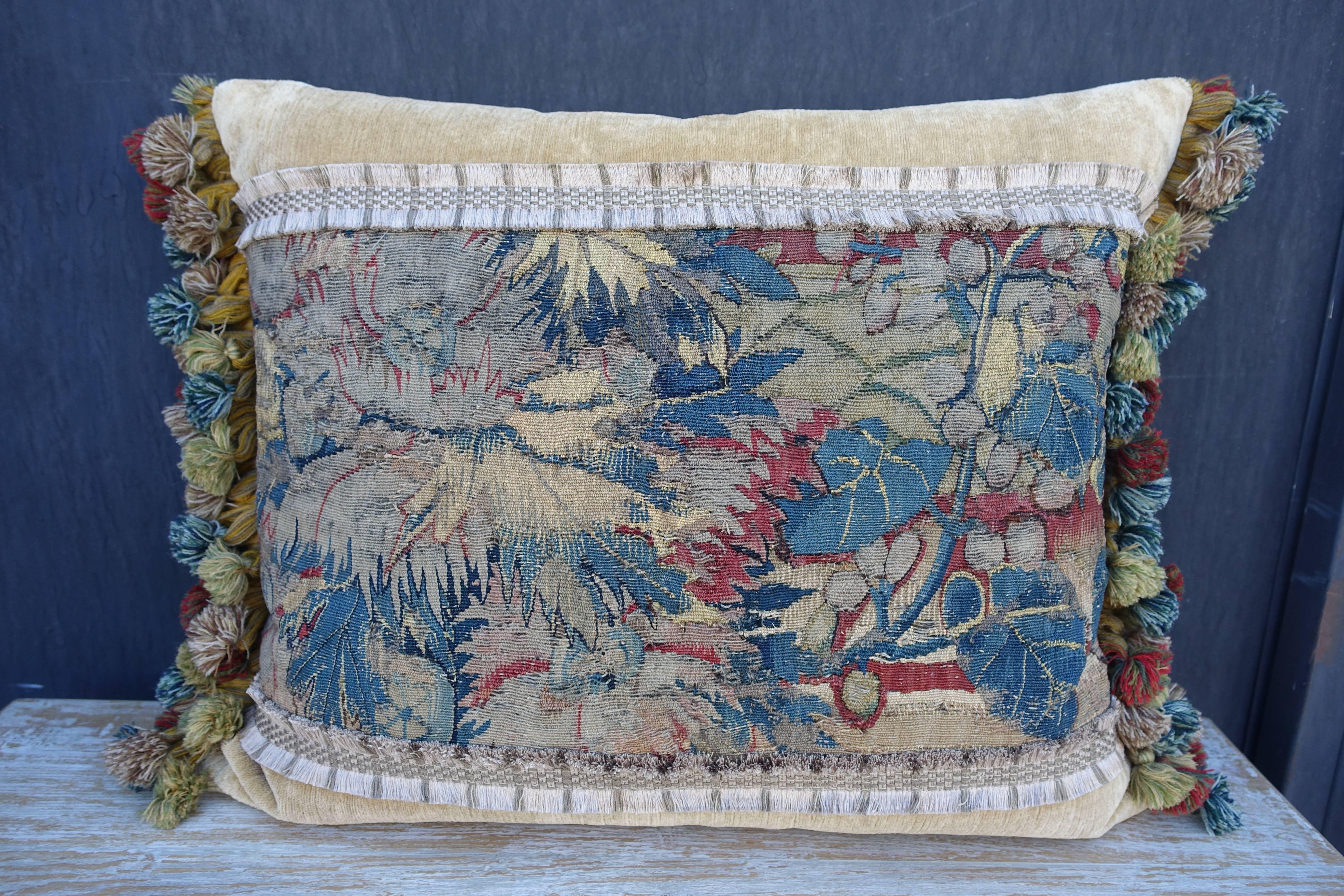 Pair of 18th century tapestry pillows adorned with fruit and flowers in rich shades of blues, greens, rust and gold on a velvet background. The pillows are finished with a multicolored coordinating tassel fringe. Down inserts, sewn shut.