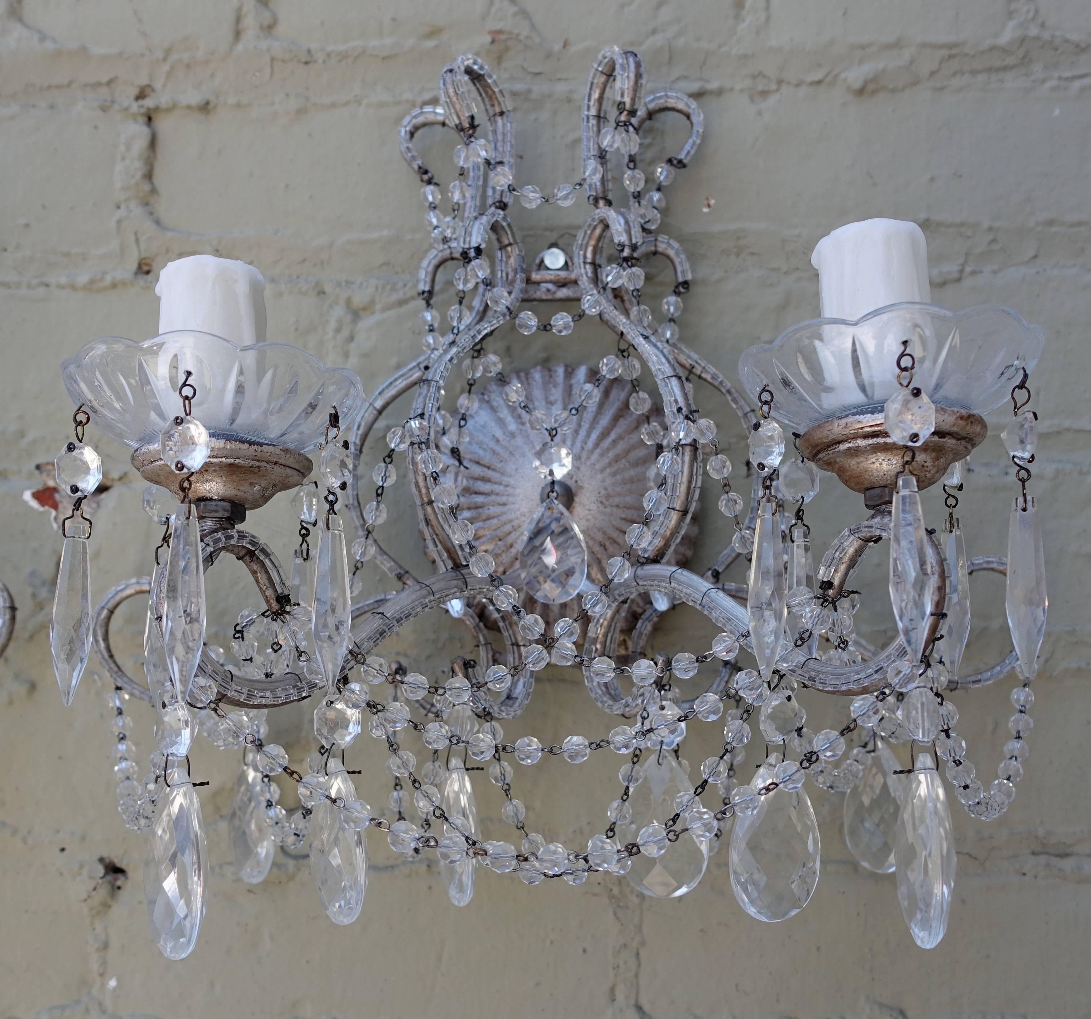 Pair of two-light silver and crystal beaded sconces. These sconces are newly wired with drip wax candle covers and are ready to install.