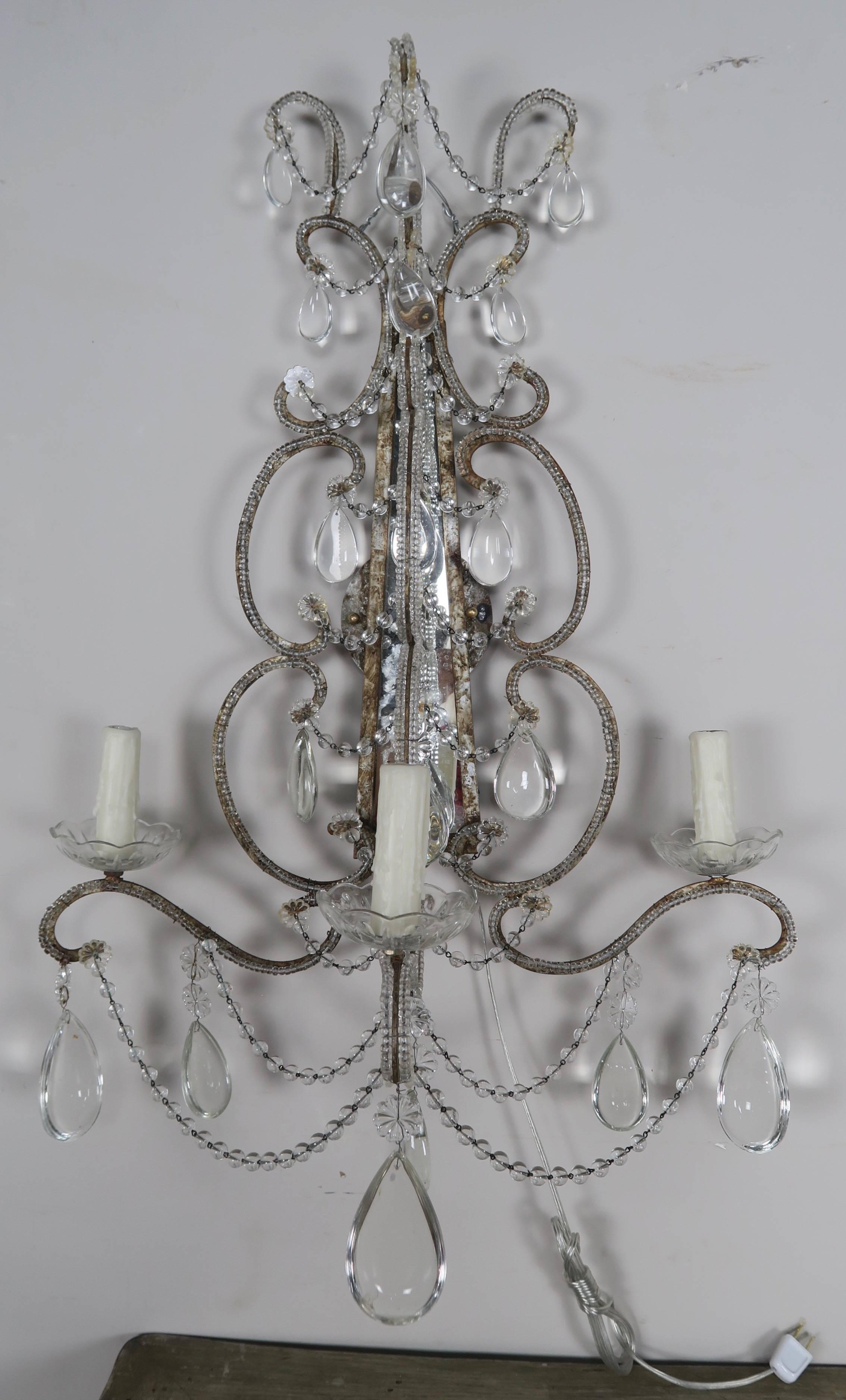 Pair of three-light crystal beaded and mirrored sconces with almond shaped crystal drops and garlands throughout. The sconces have been newly wired with drip wax candle covers.