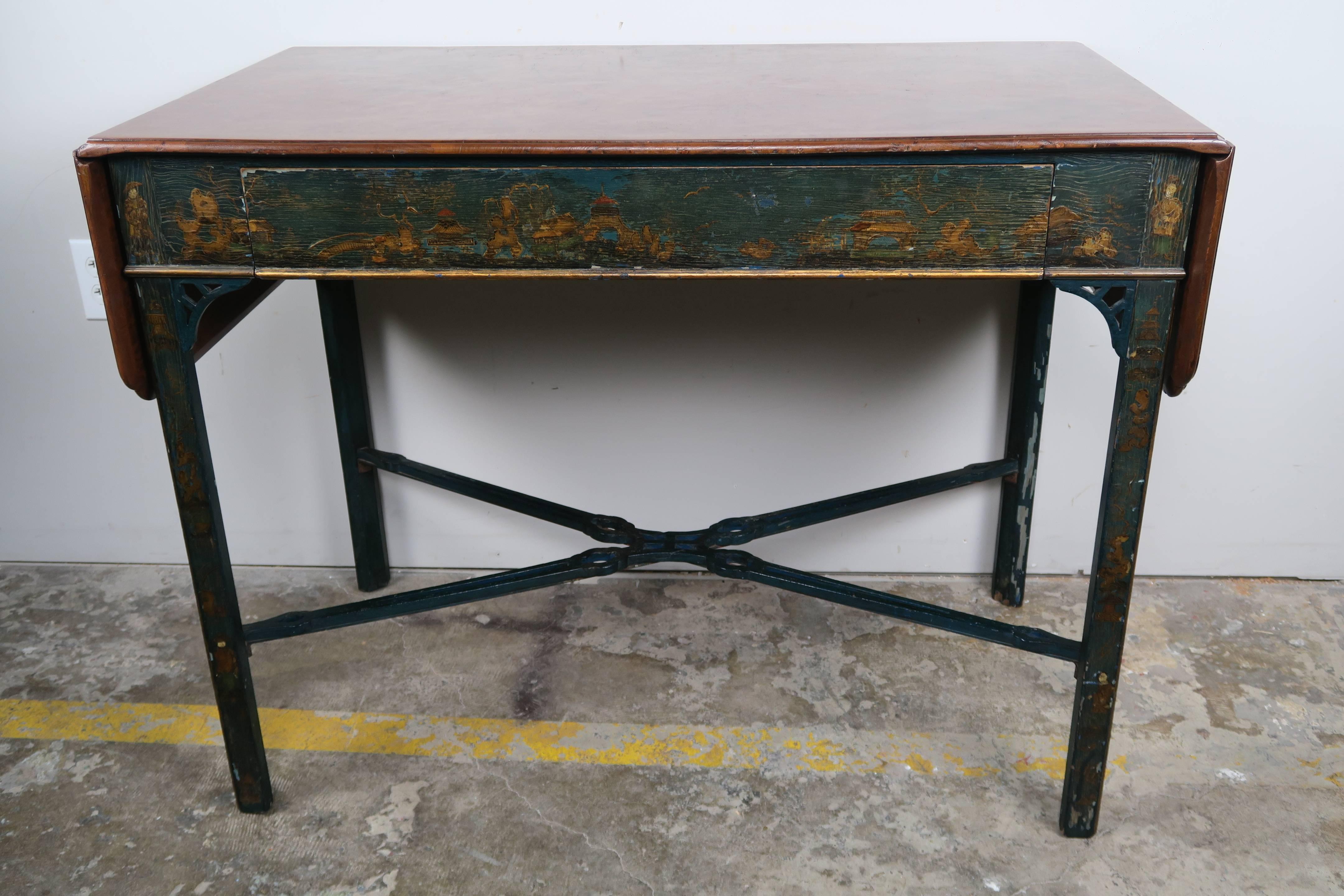 English painted teal colored chinoiserie Chippendale style table with burl walnut drop leaf top. The table has a centre drawer for storage. It stands on four straight legs connected by "X" pierced stretchers. Size of table with leaves