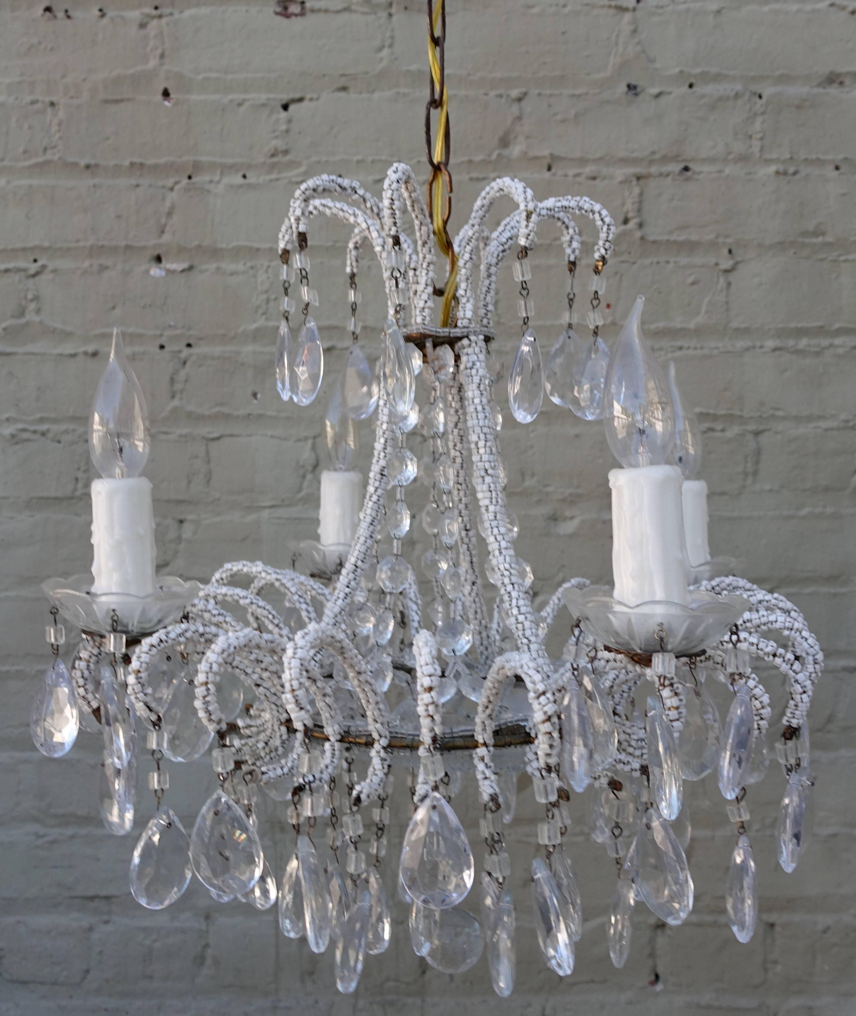 Crystal waterfall style chandelier with tiny white beads strung finely around the arms and almond shaped crystals combined with macaroni beads can be seen throughout. The fixture has been newly rewired with drip wax candle covers and crystal cups.