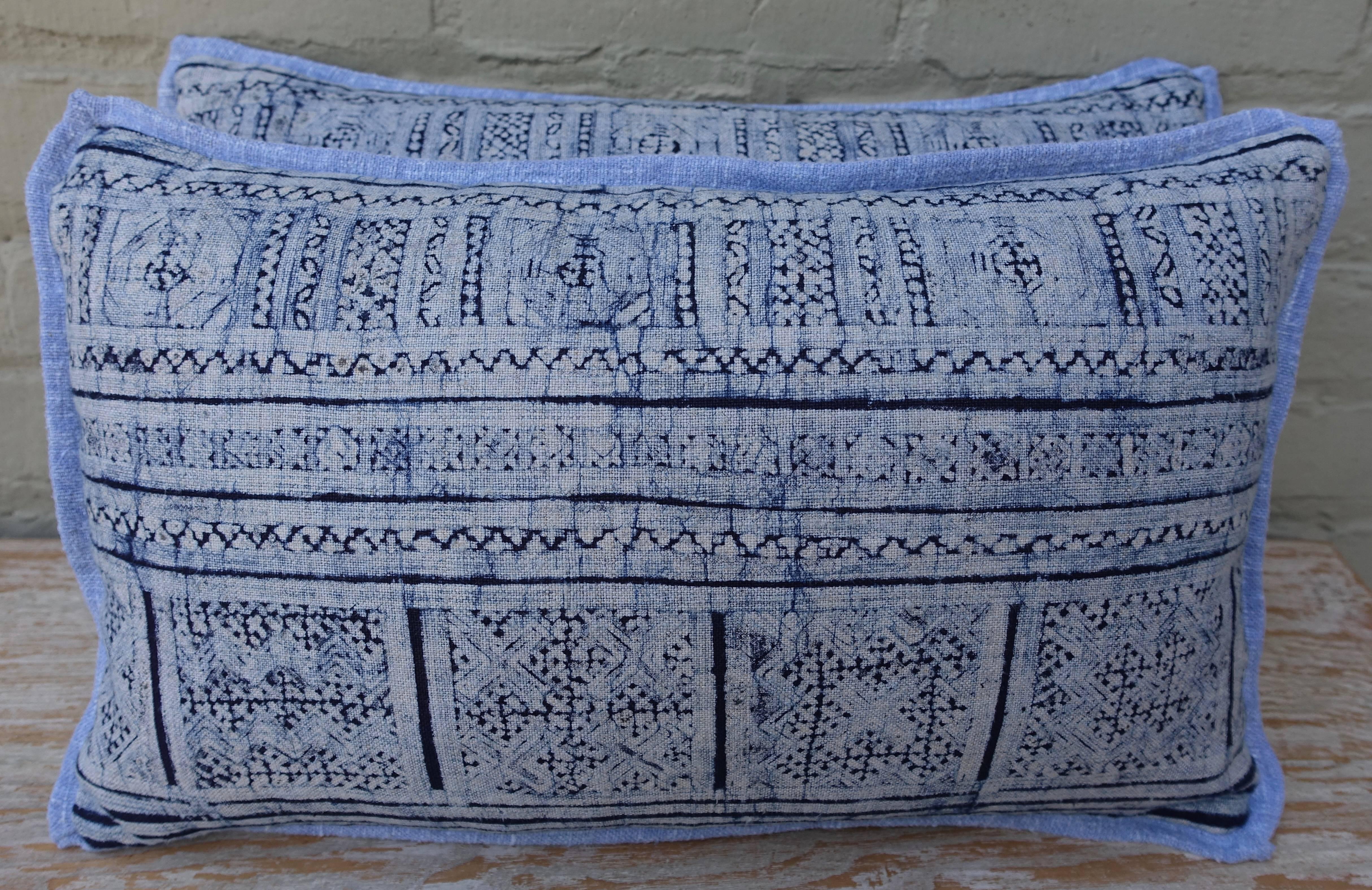 A pair of deep navy and lighter blue patterned rectangular batik pillows. Stripe, zig zag and various square block designs appear on the front with blue home spun textured linen backs. Down inserts, sewn closed.