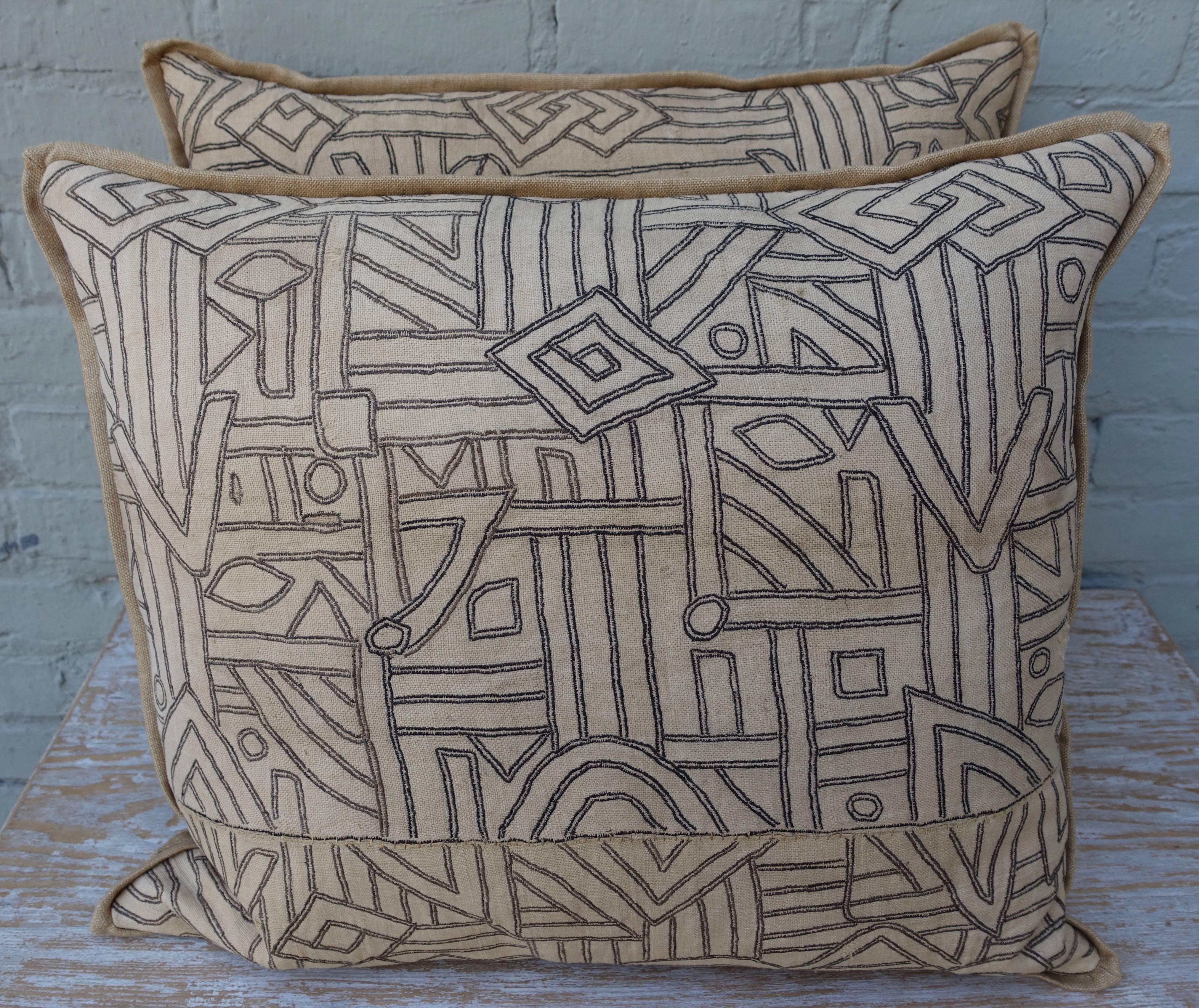 A pair of Kuba cloth pillows with geometric patterned fronts and tan linen backs. Self welt detail, down inserts, sewn closed.