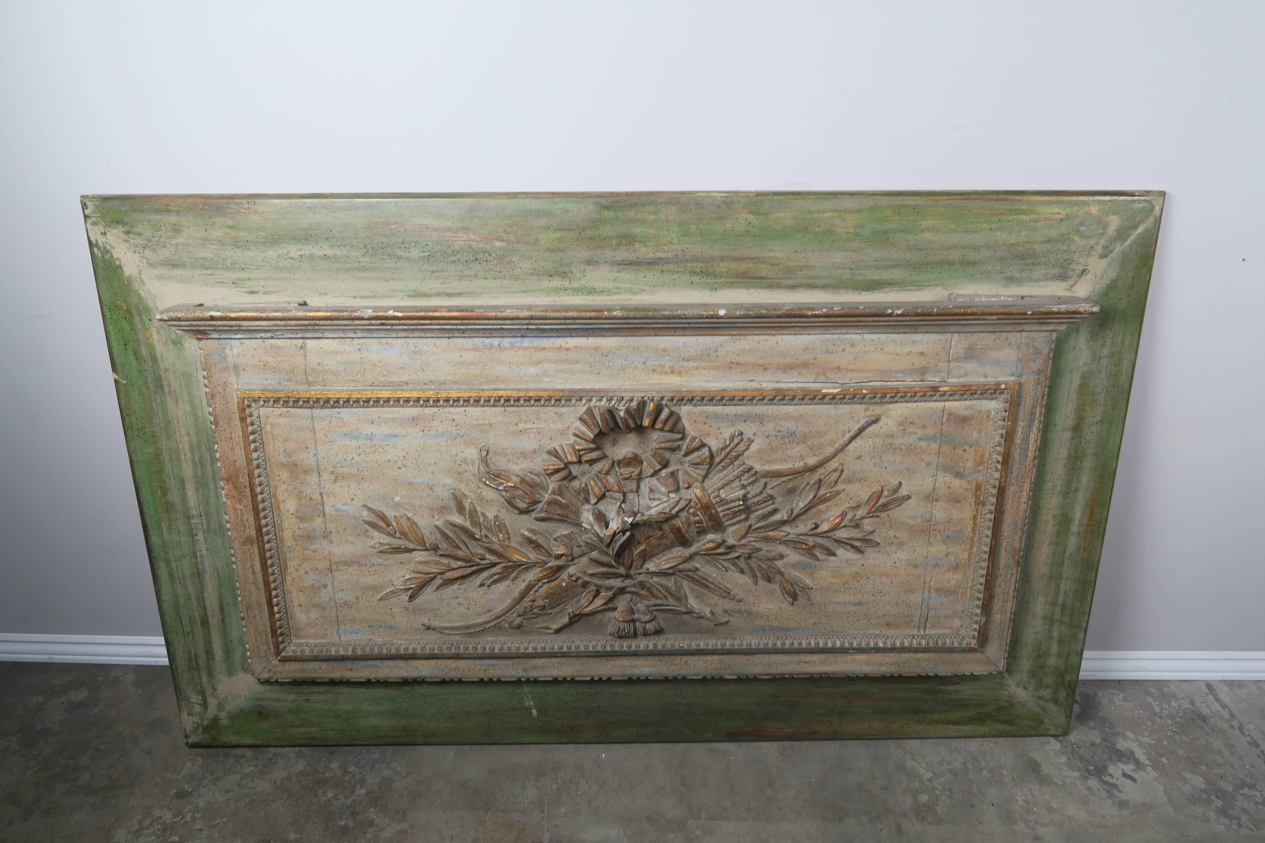 French carved wood Louis XV style painted panel depicting crossed torches, laurel leaves, bows and tassels. Soft green and cream colored painted finish with hints of gold leaf throughout.