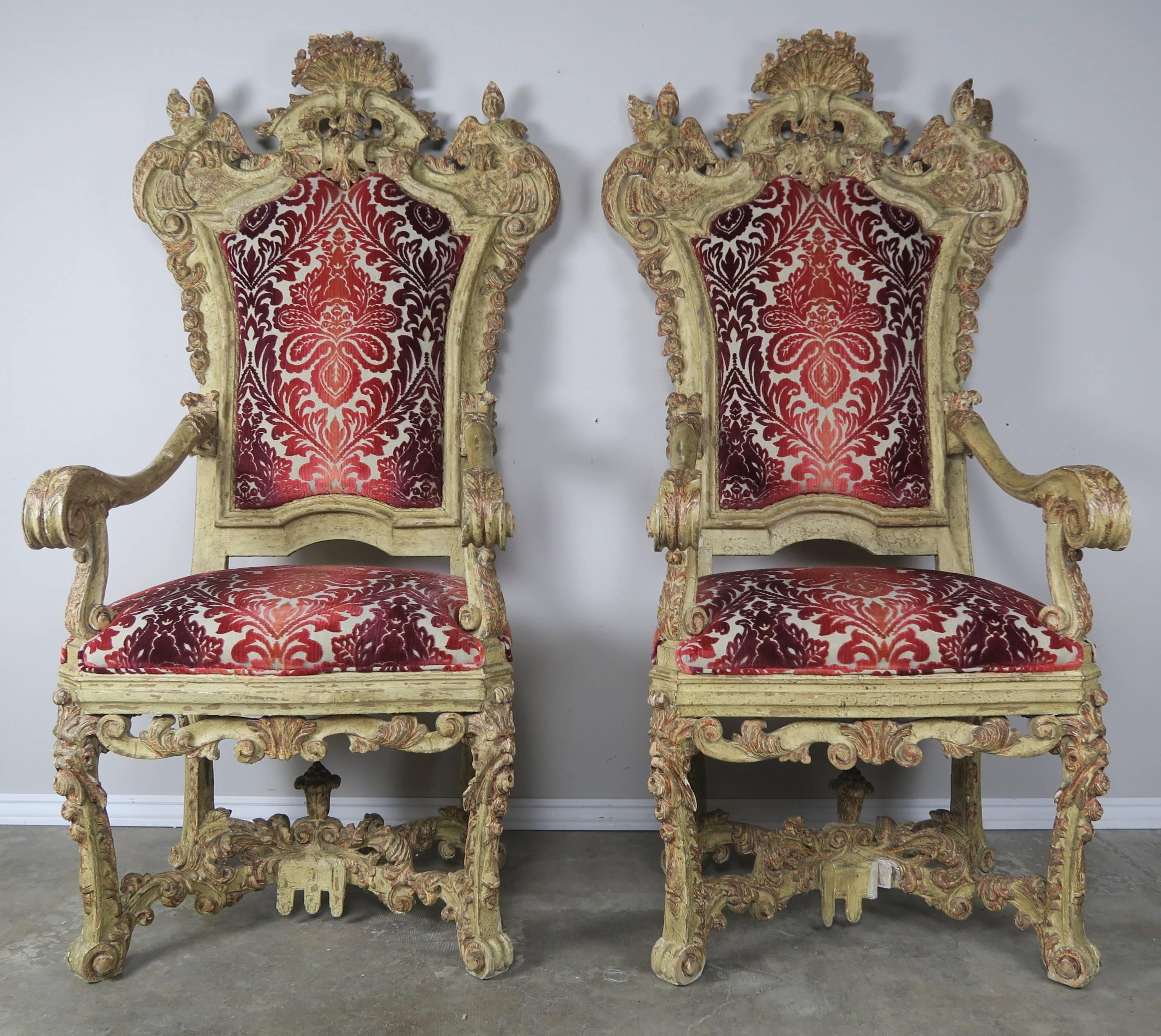 Pair of 18th century carved painted Venetian throne style armchairs. There are wonderful details carved into almost every inch of these remarkable pair of chairs. Notice the pair of winged cherubs or angels guarding the patron of the chair. The