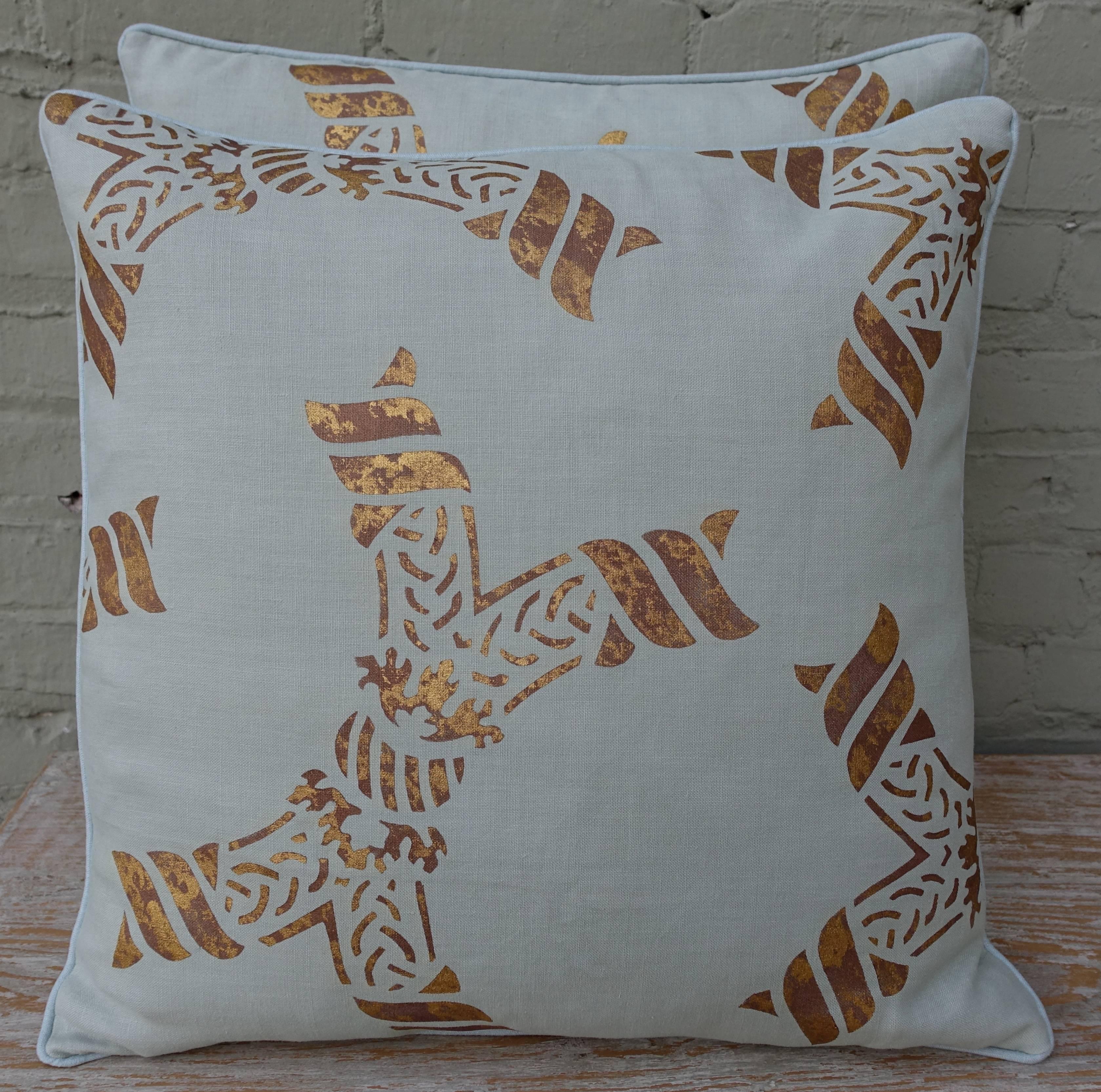 A pair of light blue gold stenciled Nomi linen pillows. Square shape with festive print design. Down inserts with self welt detail.