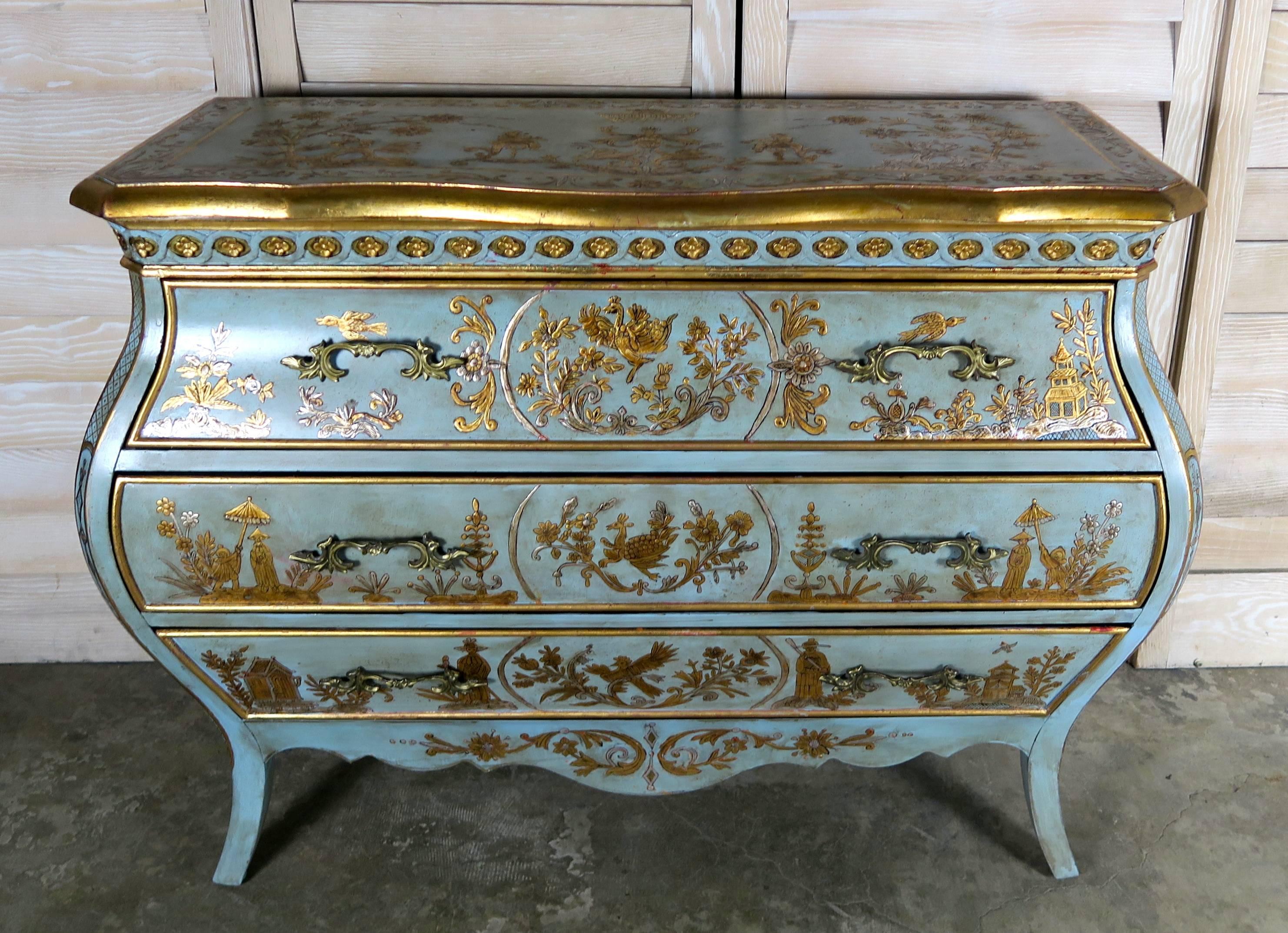 Pair of French blue painted and raised gold and silver chinoiserie Bombay shaped chests with three drawers for storage. The chests are adorned with figures, pagodas, animals, flowers and birds. Original cast brass handles.