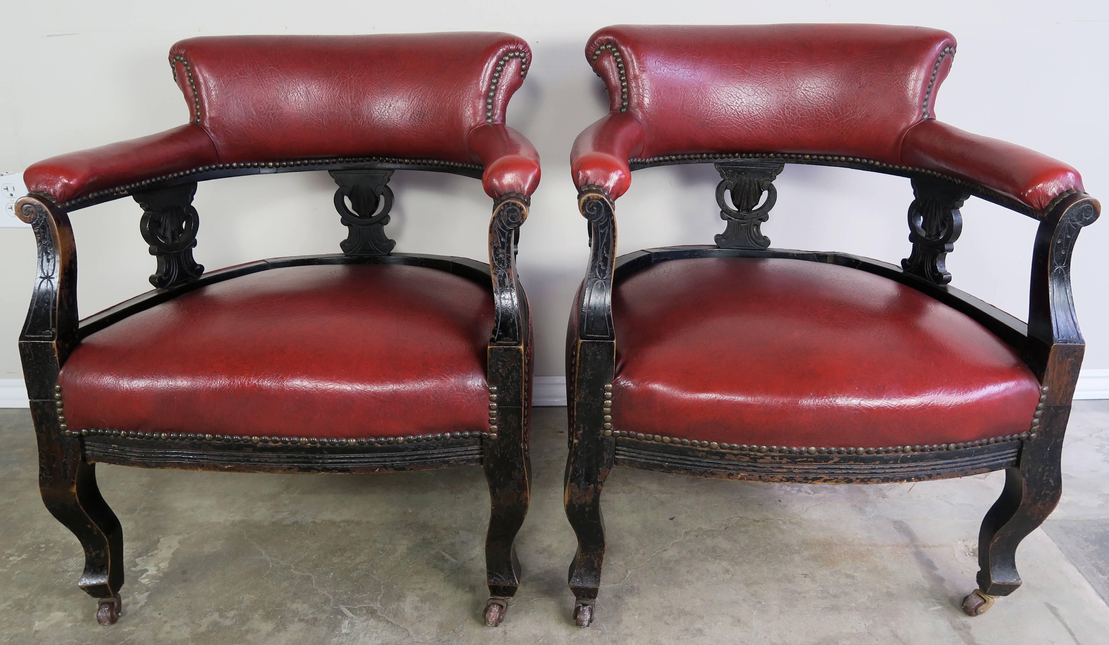 A pair of merlot colored upholstered 19th century Victorian chairs with brass nailhead trim and original antique casters.