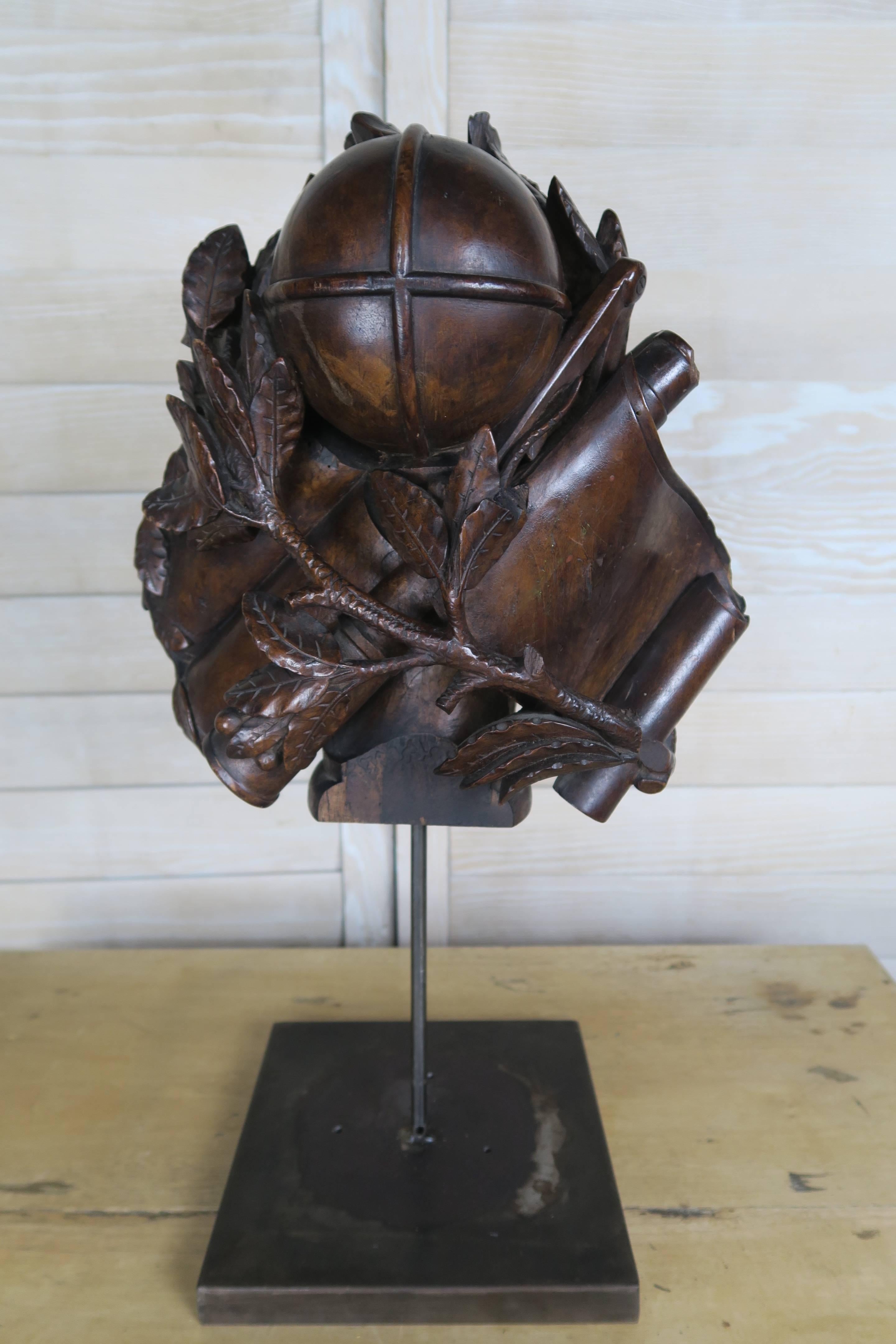 19th century hand-carved walnut remnant depicting a sphere surrounded by oak leaves and scrolls. The antique piece has been mounted on an iron base that measures 9