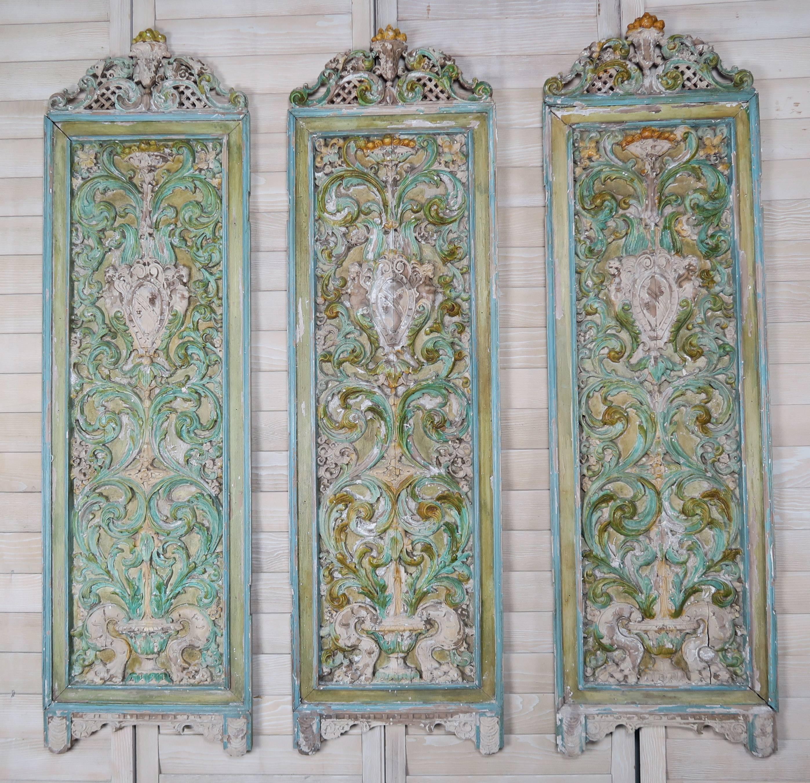 19th century Italian carved and painted 3-panel screen.  The intricate carving depicts urns with swirling acanthus leaves throughout.  Beautiful shades of greens, blues & golds.  
