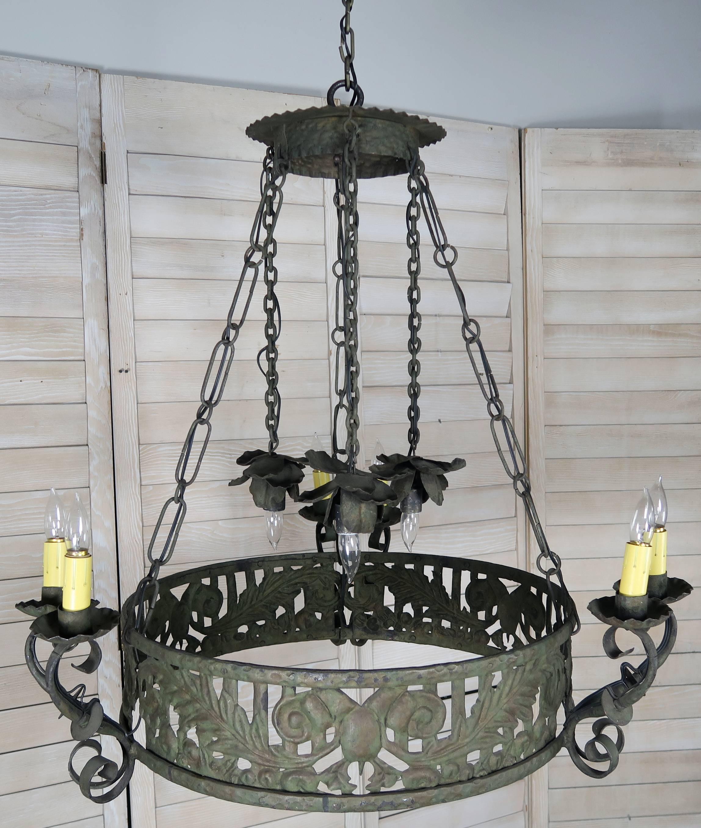 19th century Spanish wrought iron circular chandelier. Six lights in three pairs of two with drip wax candle covers held by scroll shaped arms. Three lights suspended from the canopy by wrought iron chains support three large wrought iron petaled