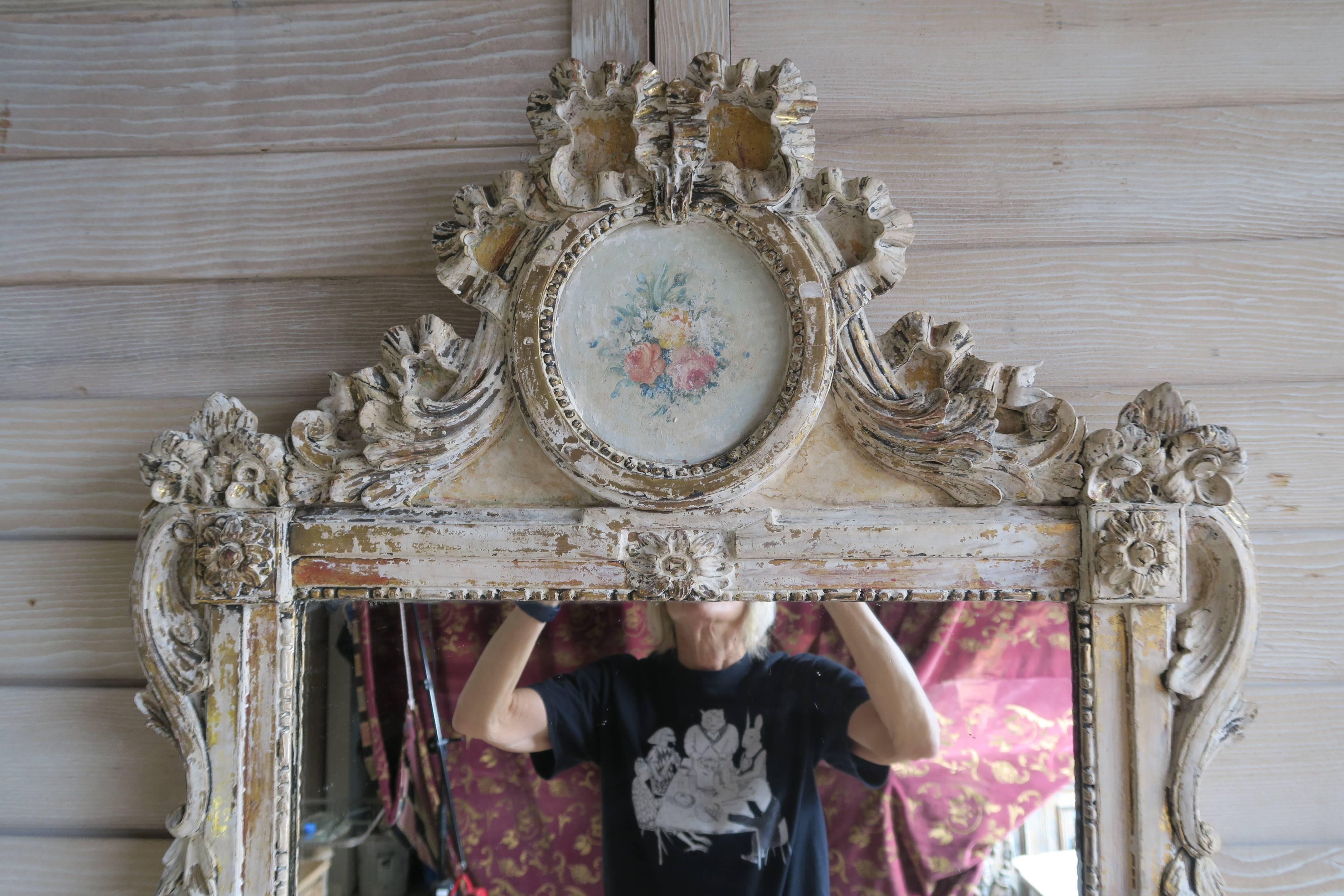 19th century French painted Louis XV style mirror with carved garlands of flowers throughout.