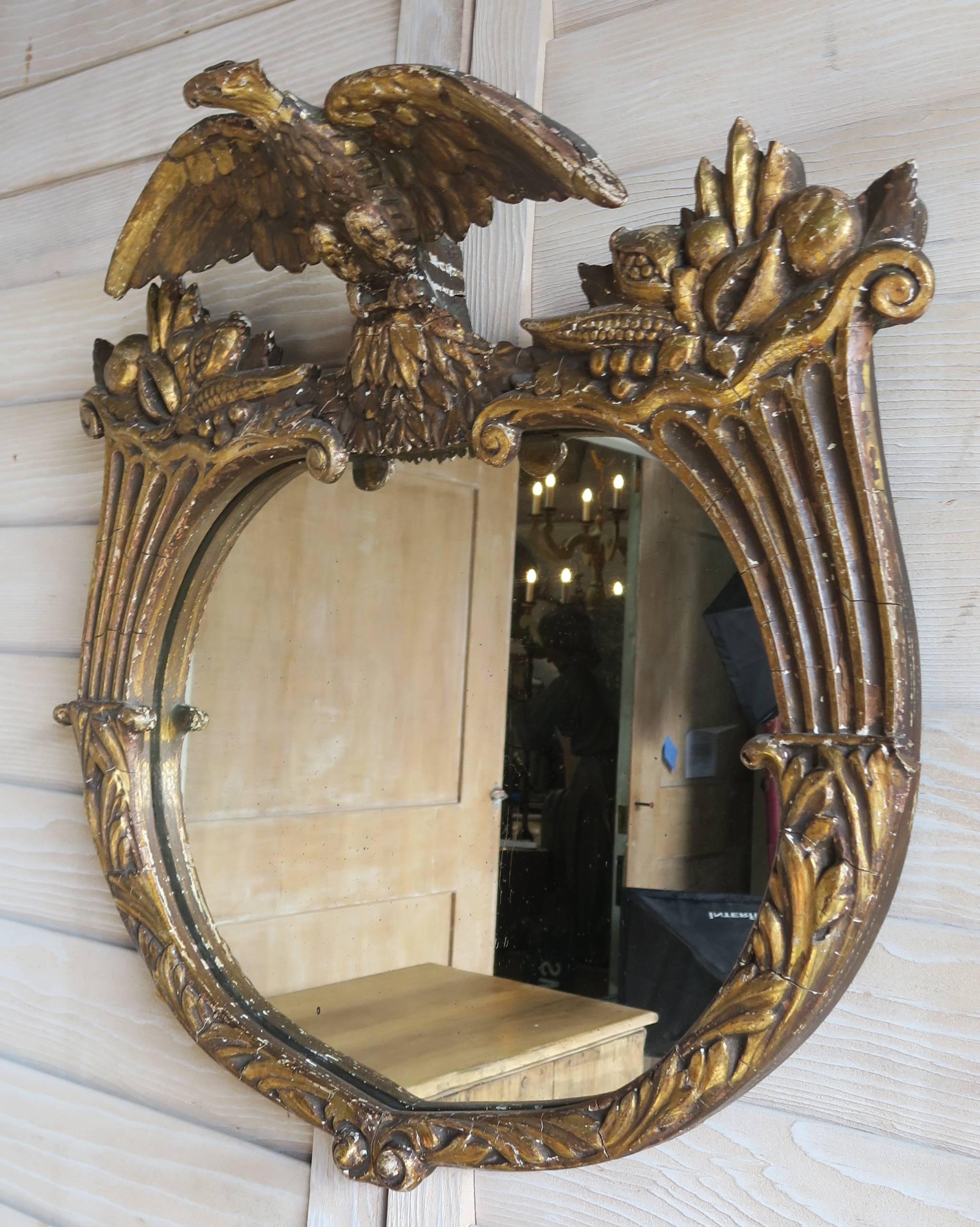 Federal style 22-karat giltwood carved mirror crowned with an eagle. The eagle is flanked by a pair of intricately carved cornucopias filled with fruit.