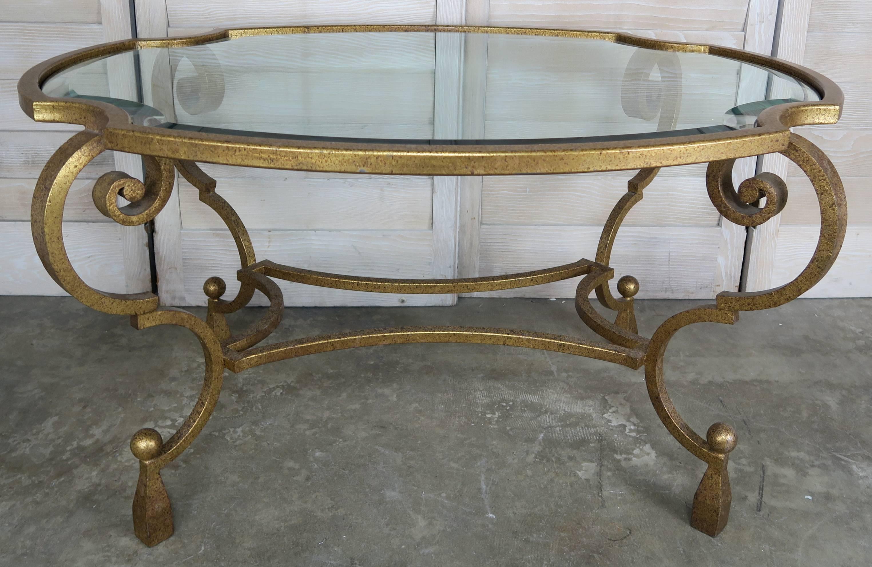 French gilt wrought iron oval shaped tea table with exaggerated cabriole legs that end in tassel feet. Inset oval glass top with 1 1/2