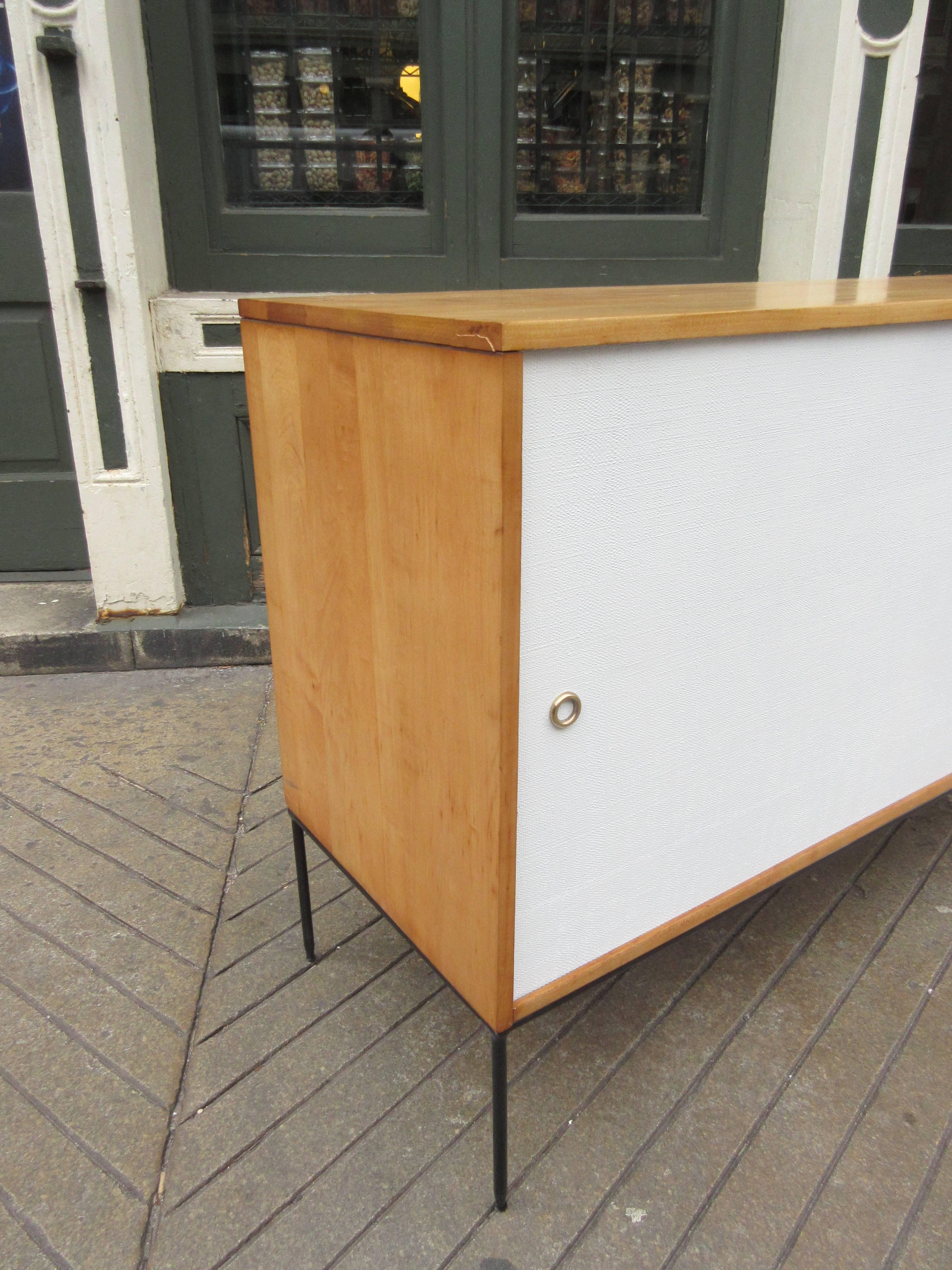 Buffet/Credenza of solid birch with painted grass cloth sliding doors on metal base. Sliding doors reveal drawers and adjustable shelving.  Retains branded labeling. Beautifully refinished. 