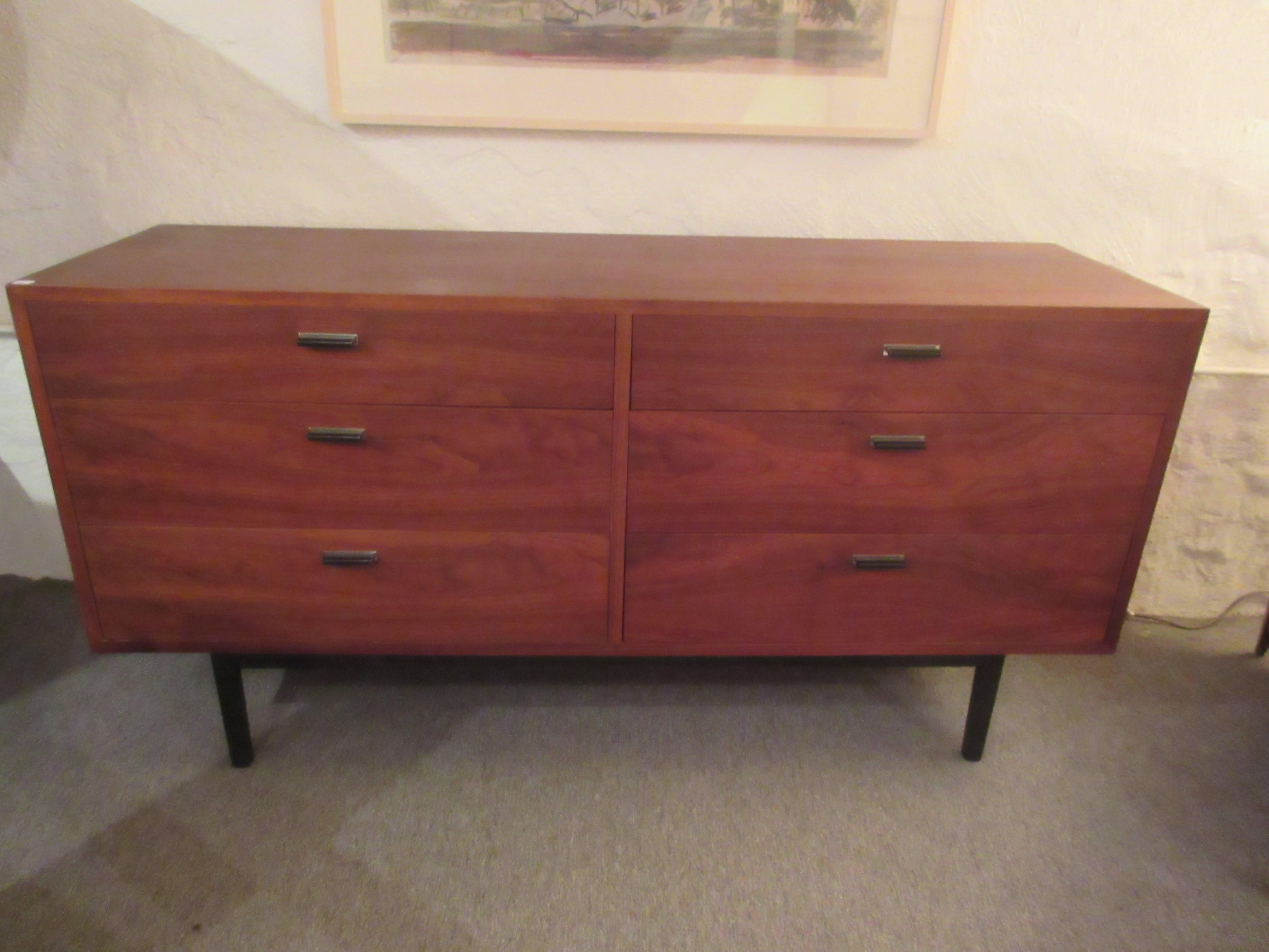 American Mid-Century walnut dresser on ebonized wooden legs with pulls of painted cast metal on a rectangle of chrome.