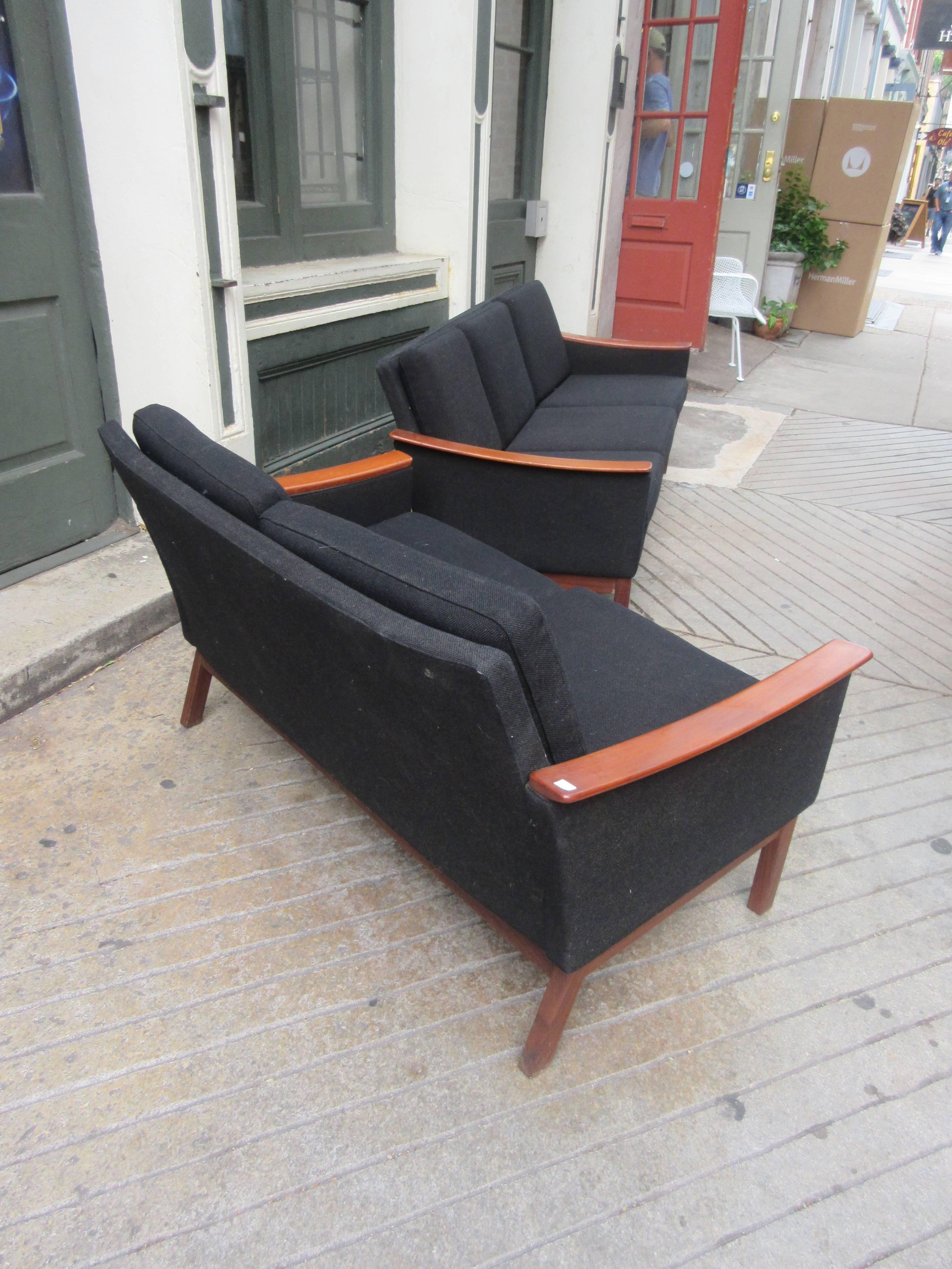Suite consists of chair, settee and sofa in original black hopsack wool fabric. The swooping teak arms have certainly served to save the fabric. All pieces are of the same height and depth differing only in width with arm being identical. Measures: