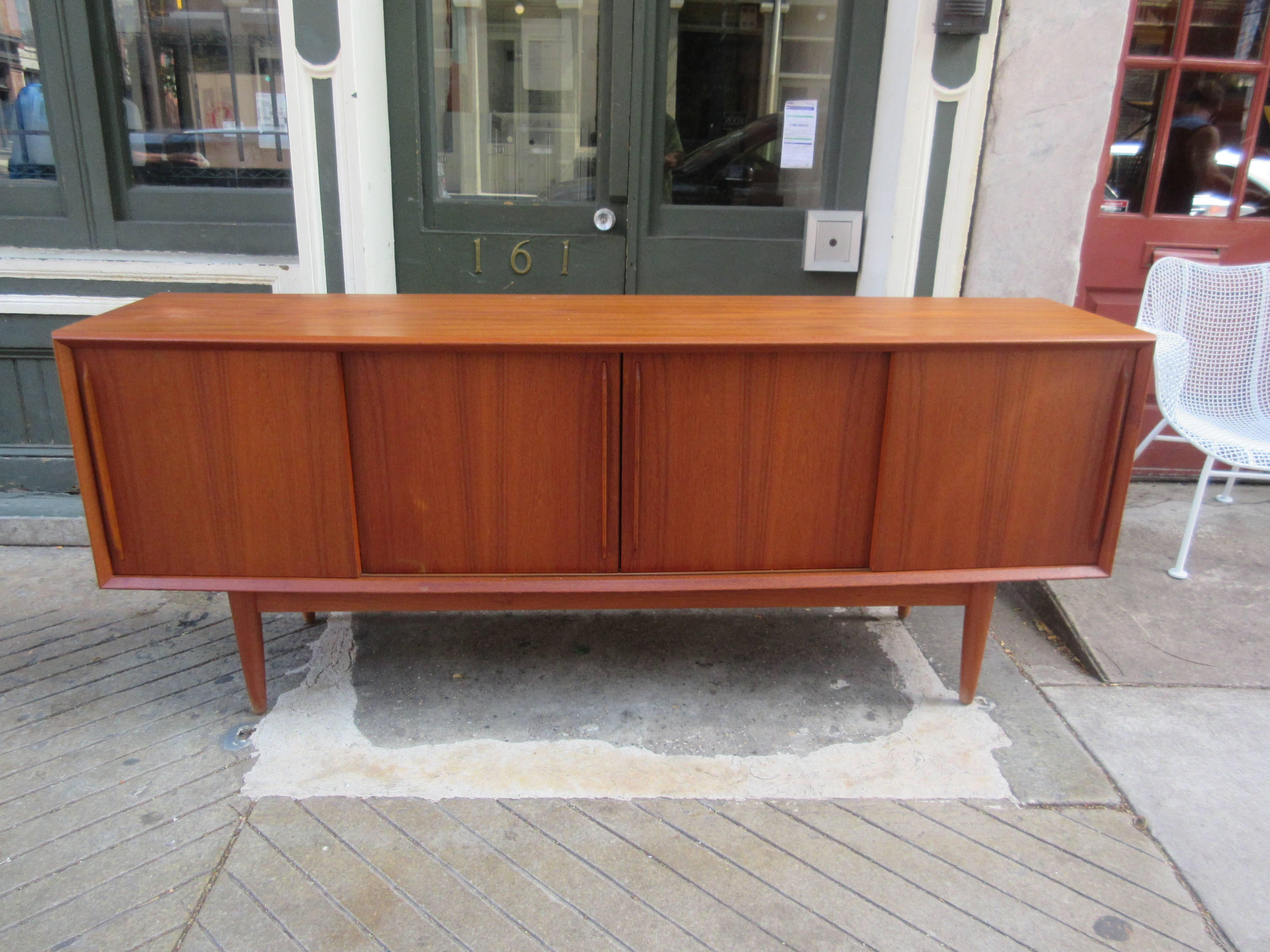 Great design teak credenza with a bowed front, very slight curve comes out in the middle 2" more than ends. Beautiful rich teak grain and color, all original! four sliding doors reveal pull-out drawers on the left, double open area in middle