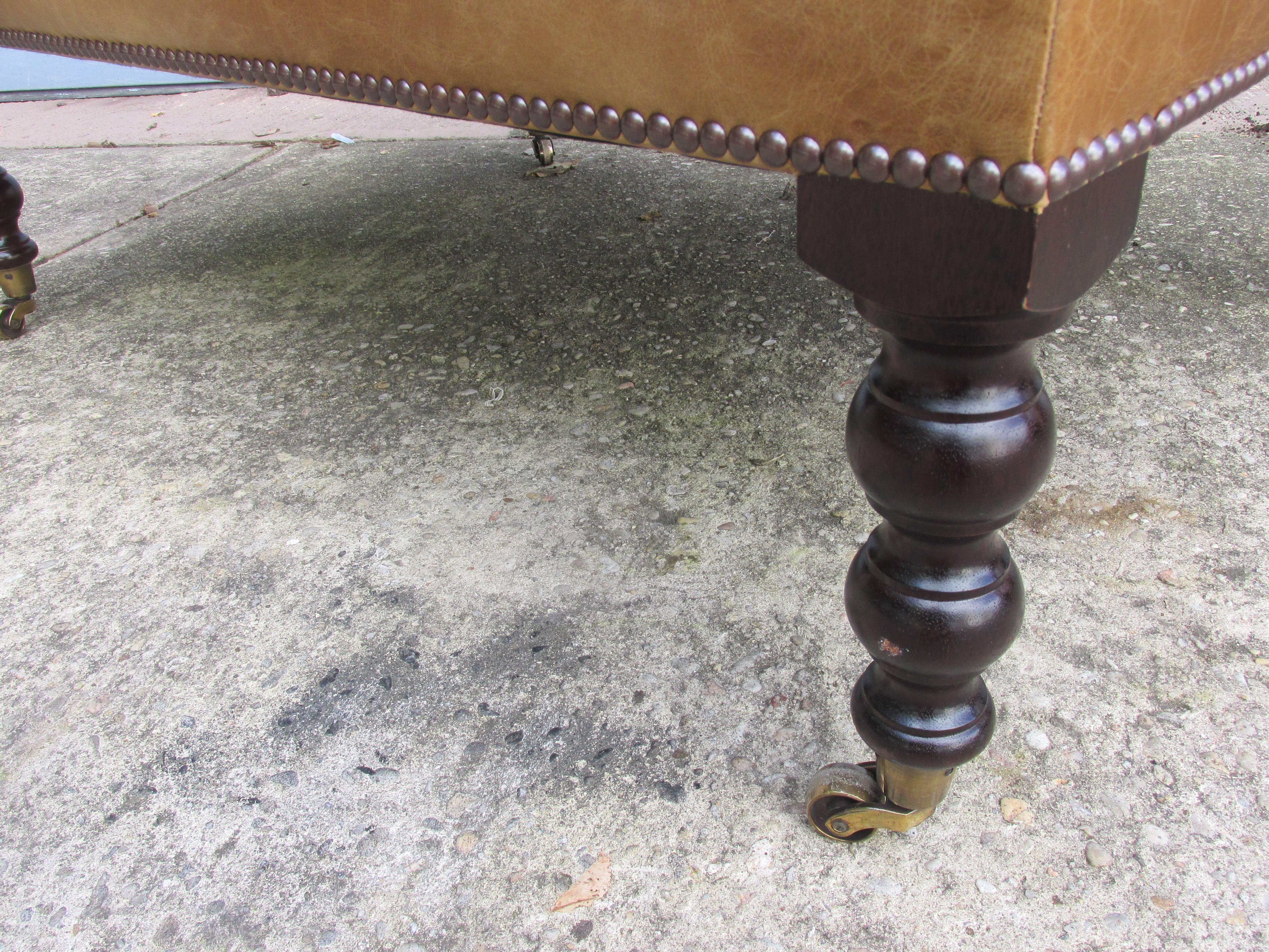 Rectangular leather Ottoman from the mid- 1990s. Nicely turned walnut legs with brass castors. Retains original labels. Pair of matched leather chairs available in a separate listing.