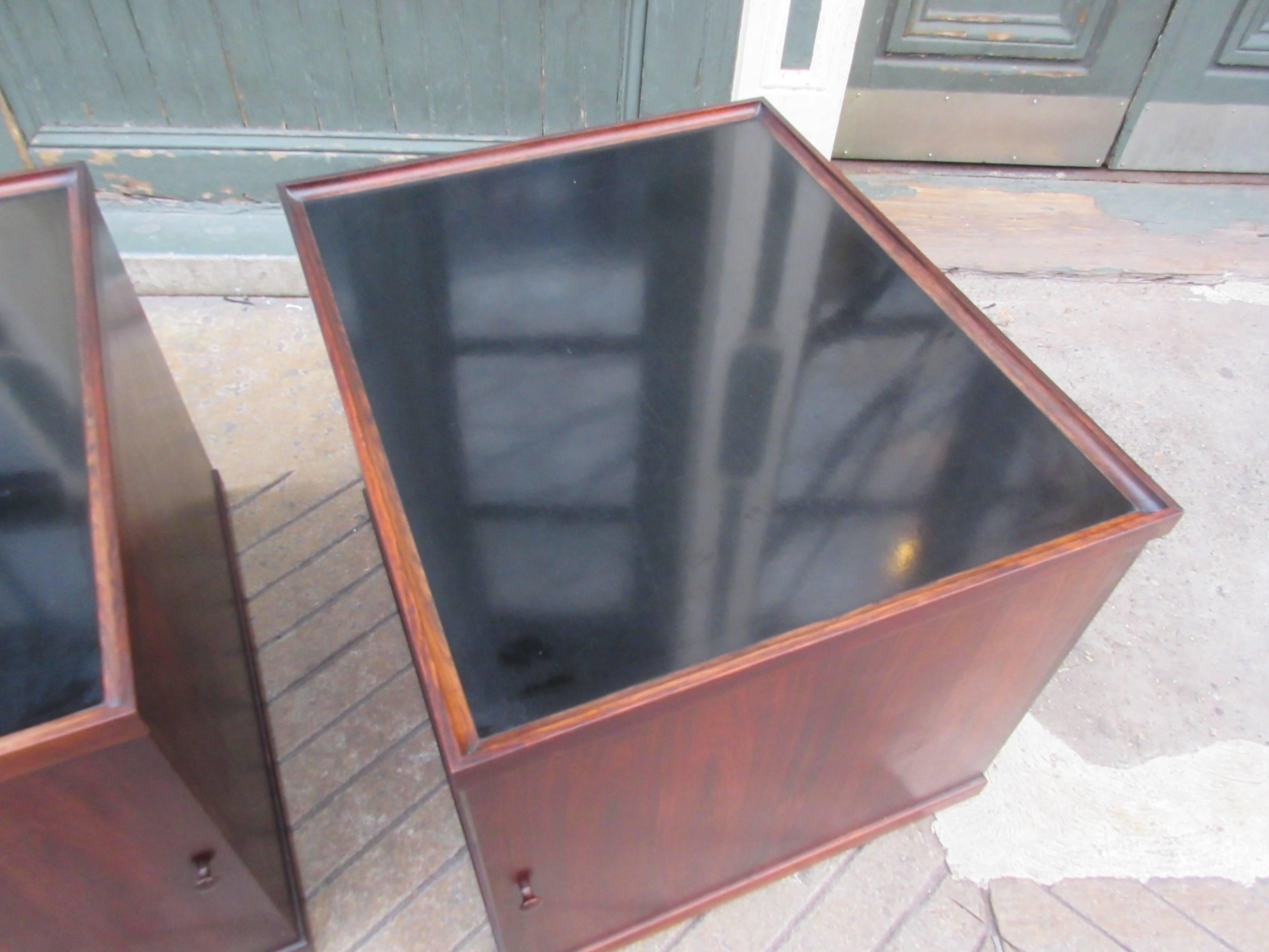 These rosewood cubes with black laminate tops have single doors which reveal shelving for glasses and an open center space for bottles making matching sofa end tables which double as bars. They were bought in Denmark in the late 1950s and are