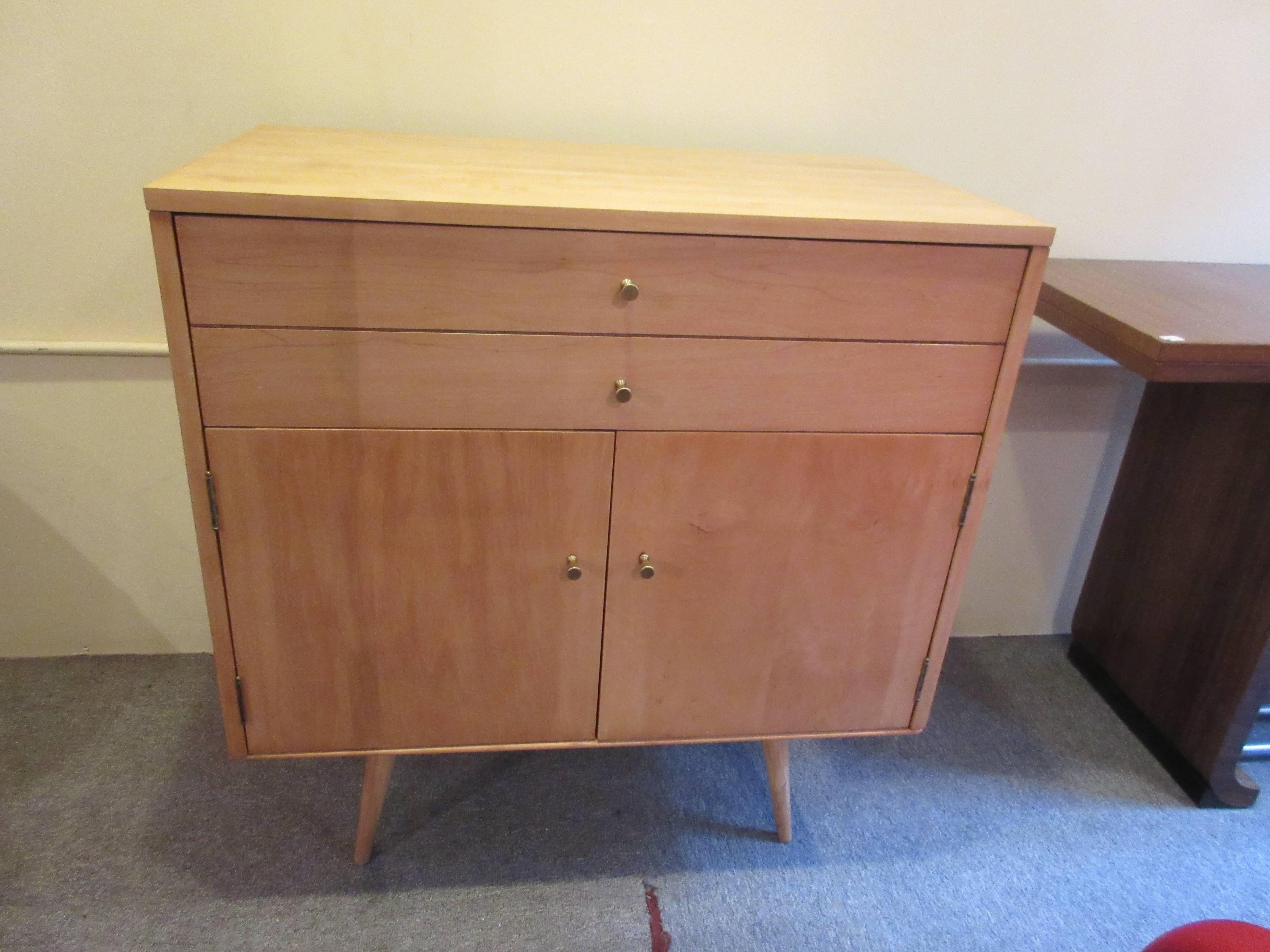 Sweet 32 inch cabinet on Planner Group bench with unusual top double drawer. Recently refinished and open space has an adjustable shelf. Handles are the brass hourglass shape.