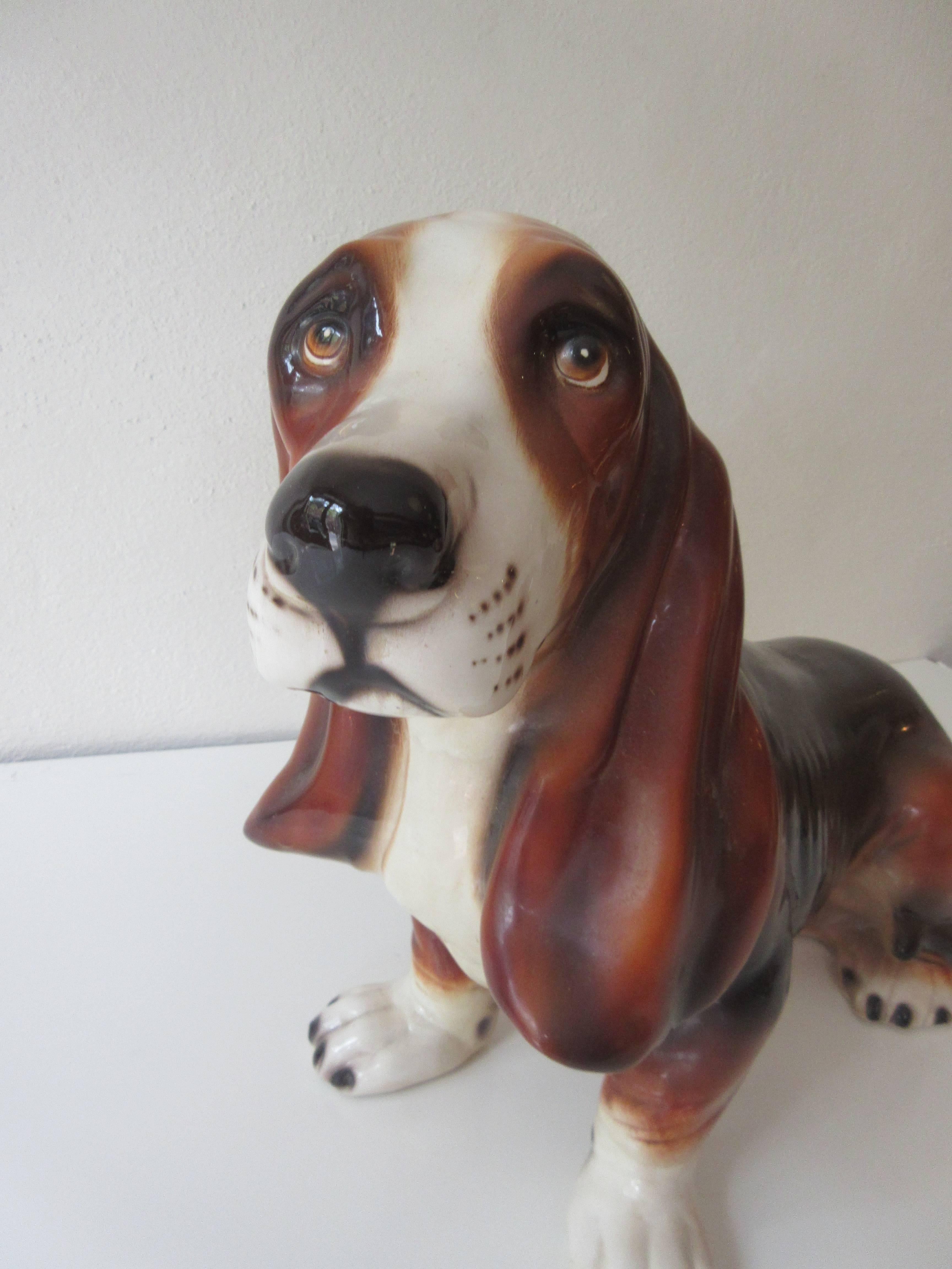 Ceramic Bassett Hound incised Montebello made in Italy with symbol. One chip on underside rear foot not visible when sitting down. Single hole drilled on stomach purpose unknown, this adorable beastie has Bette Bassett eyes and realistic coloring