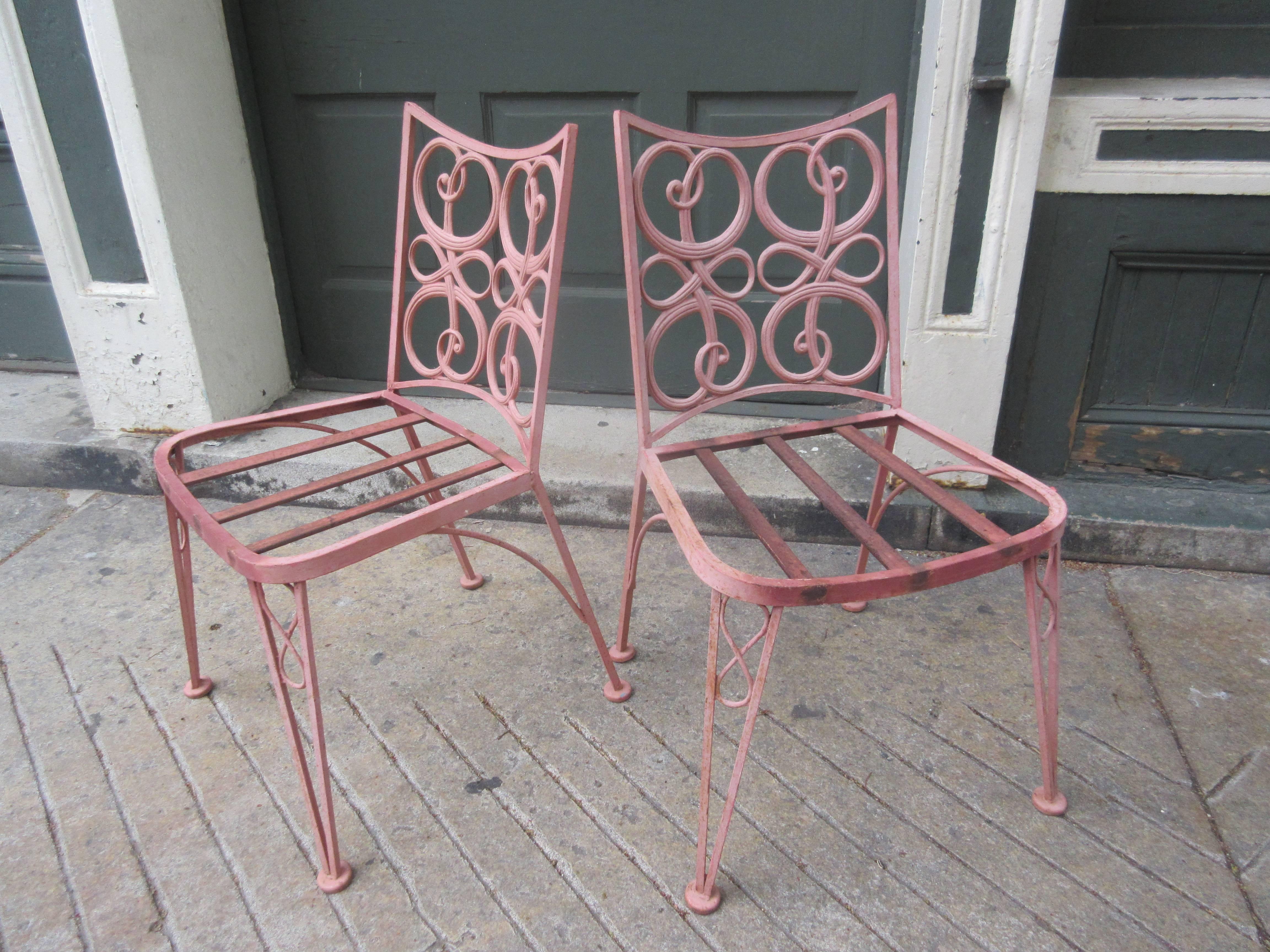 1950s or early 1960s cast metal patio set. Table base and chair backs are made up of interlocking loops. Set retains old, possibly original pink paint! Set looks good with the current patina or inquire about having the set powder coated in any color