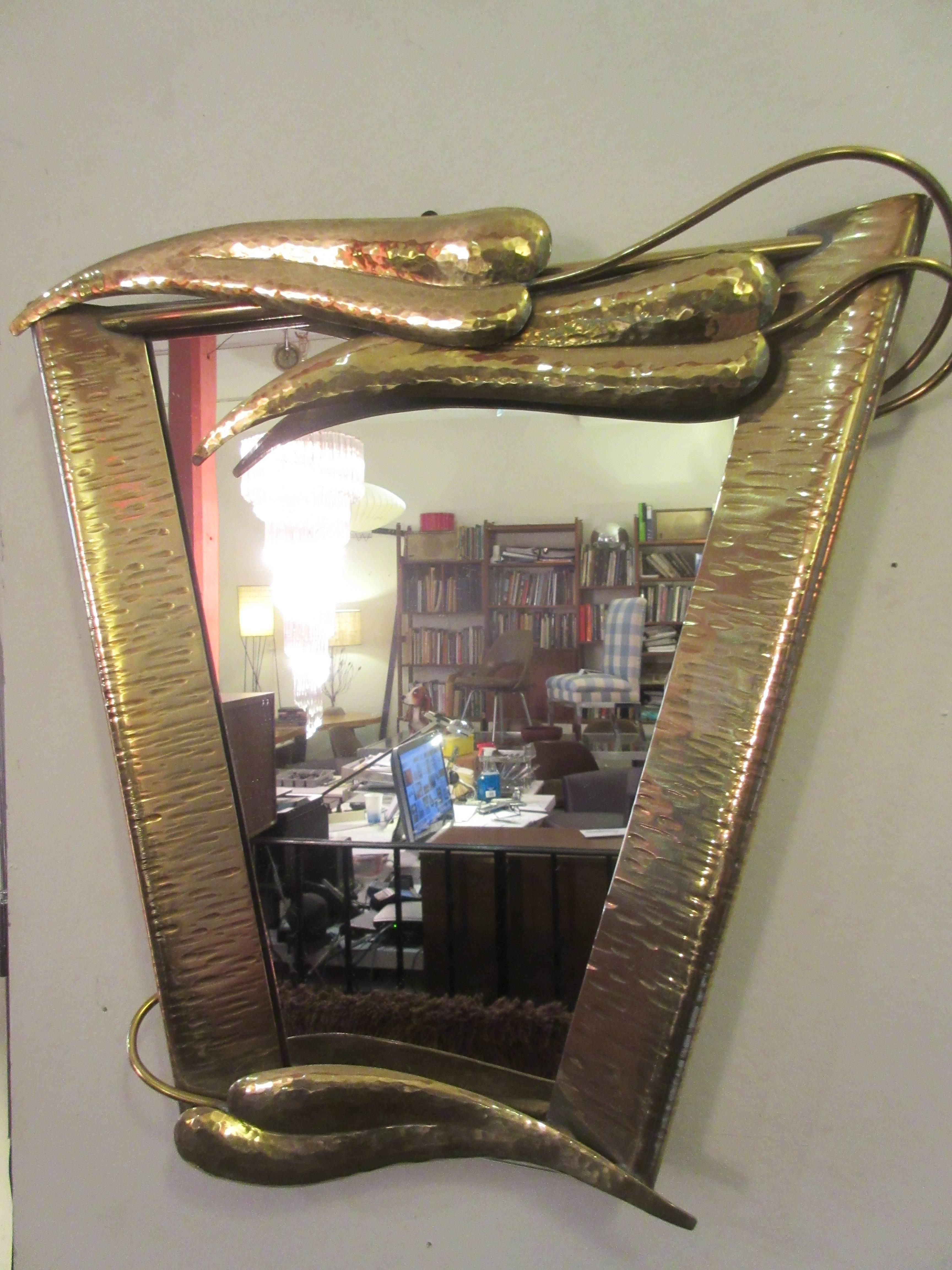 Diminutive brass mirror in the style of Wiener Werksatte with tendrils of leaves encircling the trapezoidal glass. The appearance exaggerates the three dimensional quality of this piece. There is one old repair to on tendril (pictured) which does