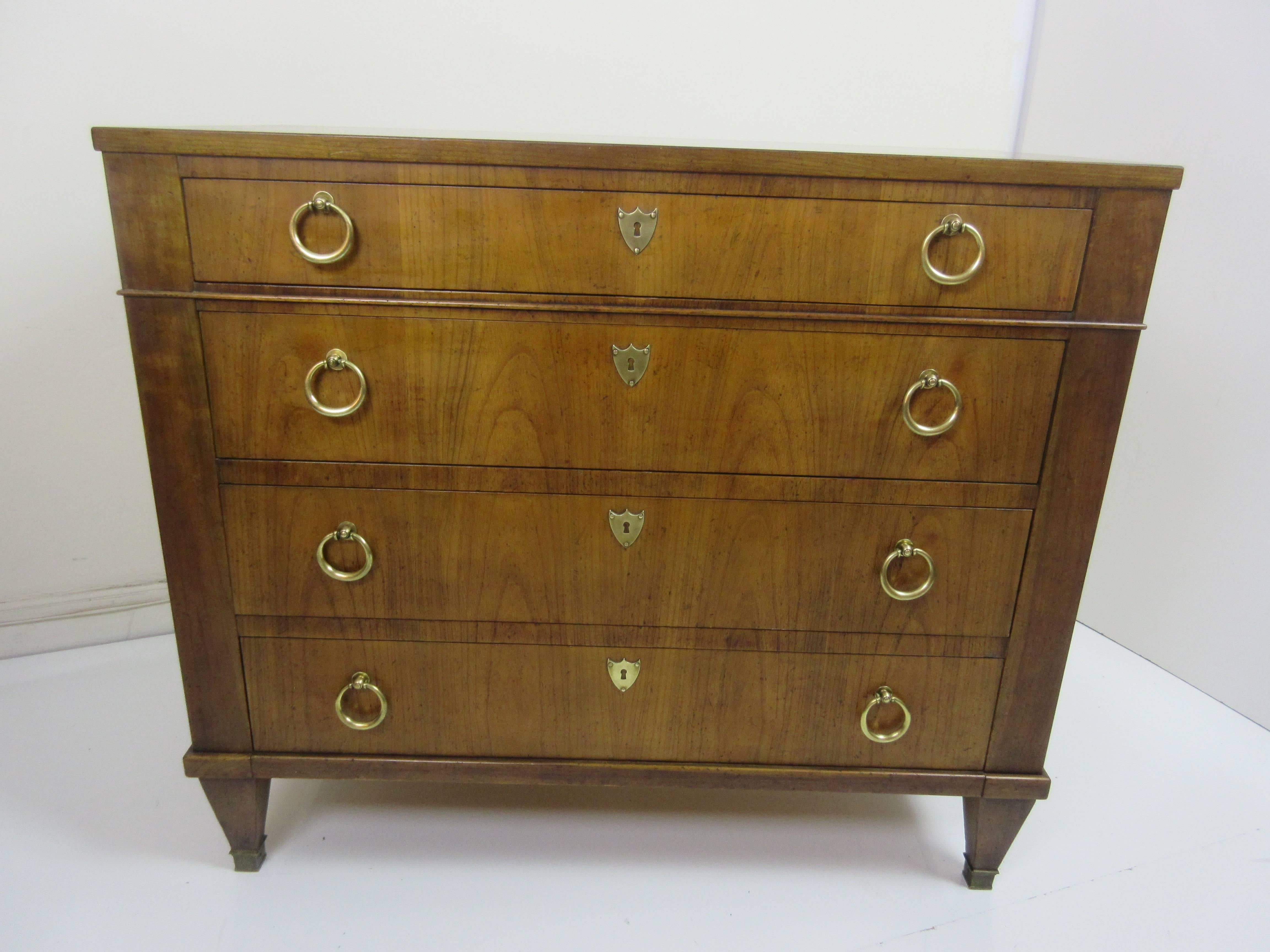 Four-drawer late 1950s neoclassical dresser by Baker Furniture. Solid round brass rings and shield shaped key covers. Very clean original condition! All drawers function beautifully!