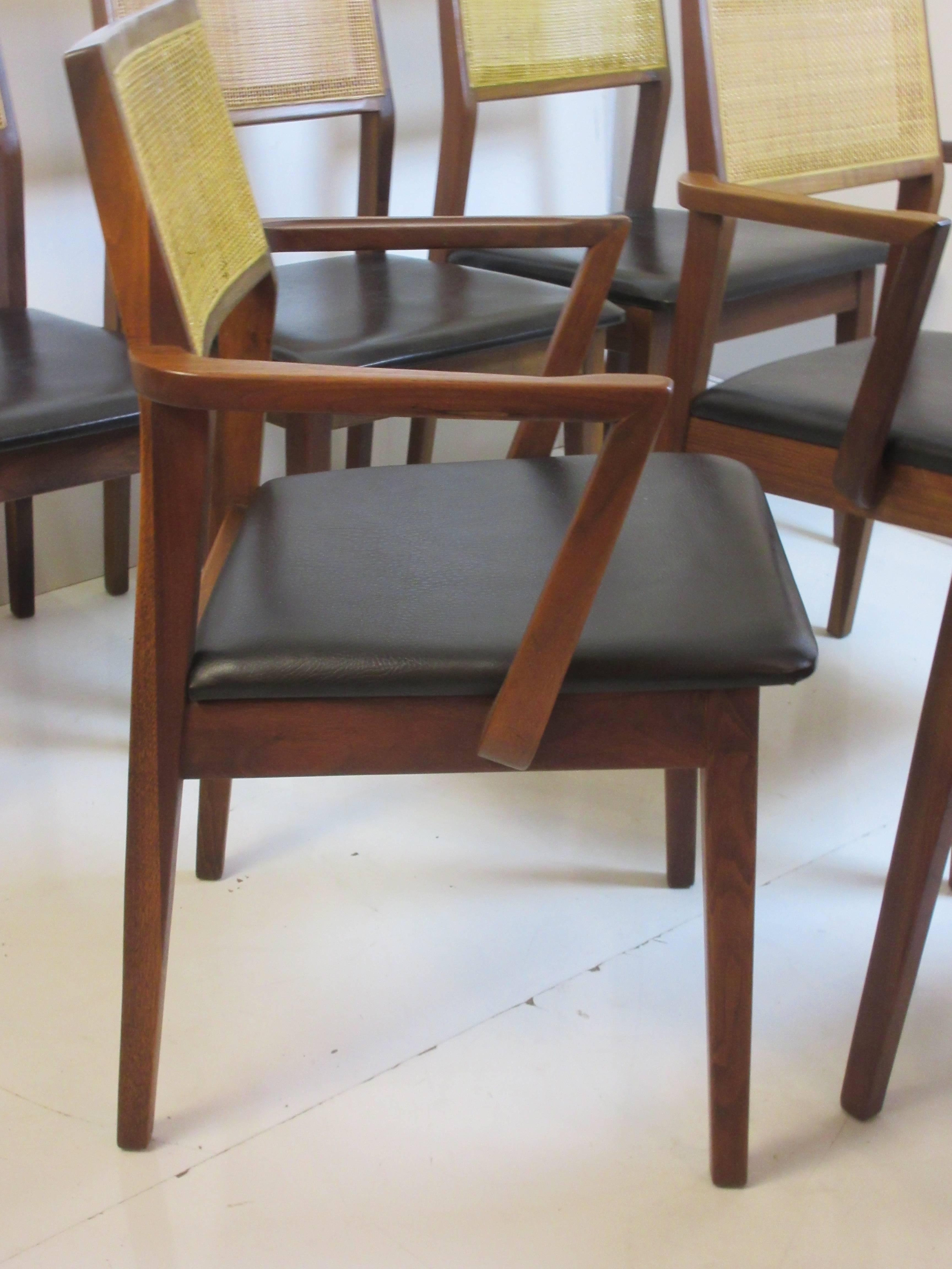 Founders for Thomasville walnut Jack Cartwright dining chairs with caned backs and original black vinyl seats. Both caning and vinyl in great shape. Seats are easily removed for re-upholstering. Chairs are remarkably small in scale but yet as
