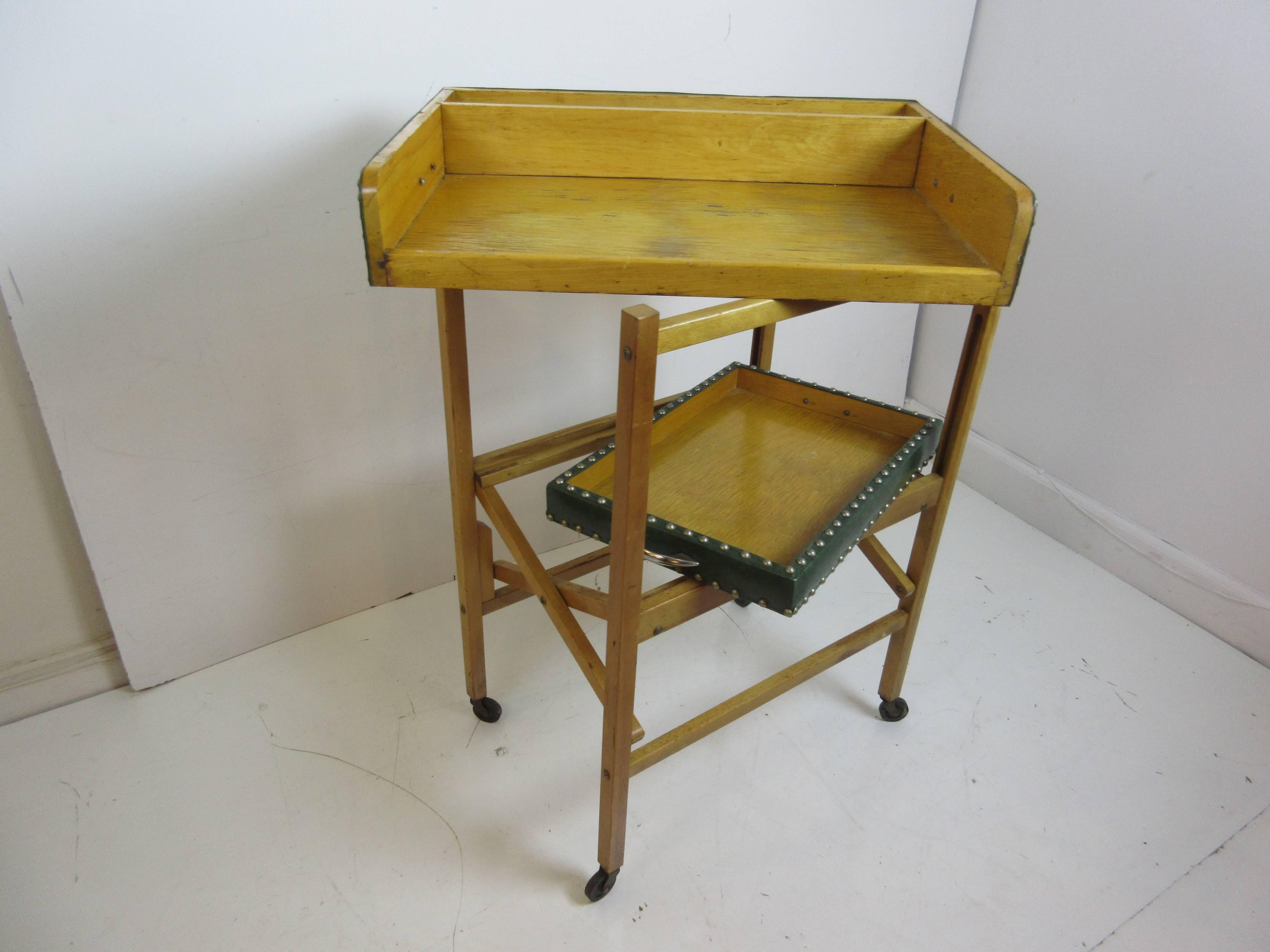 Drink trolley with two removable serving trays and supported by a folding Stand. Trays are covered in a green vinyl with brass hobnail tacks.