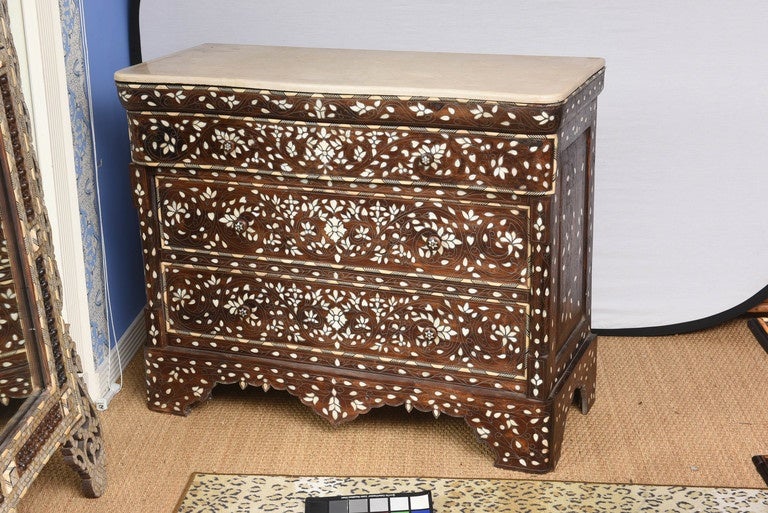 A Syrian inlaid mother-of-pearl, silver, bone and oak three-drawer commode dresser with a marble top, 19th century.