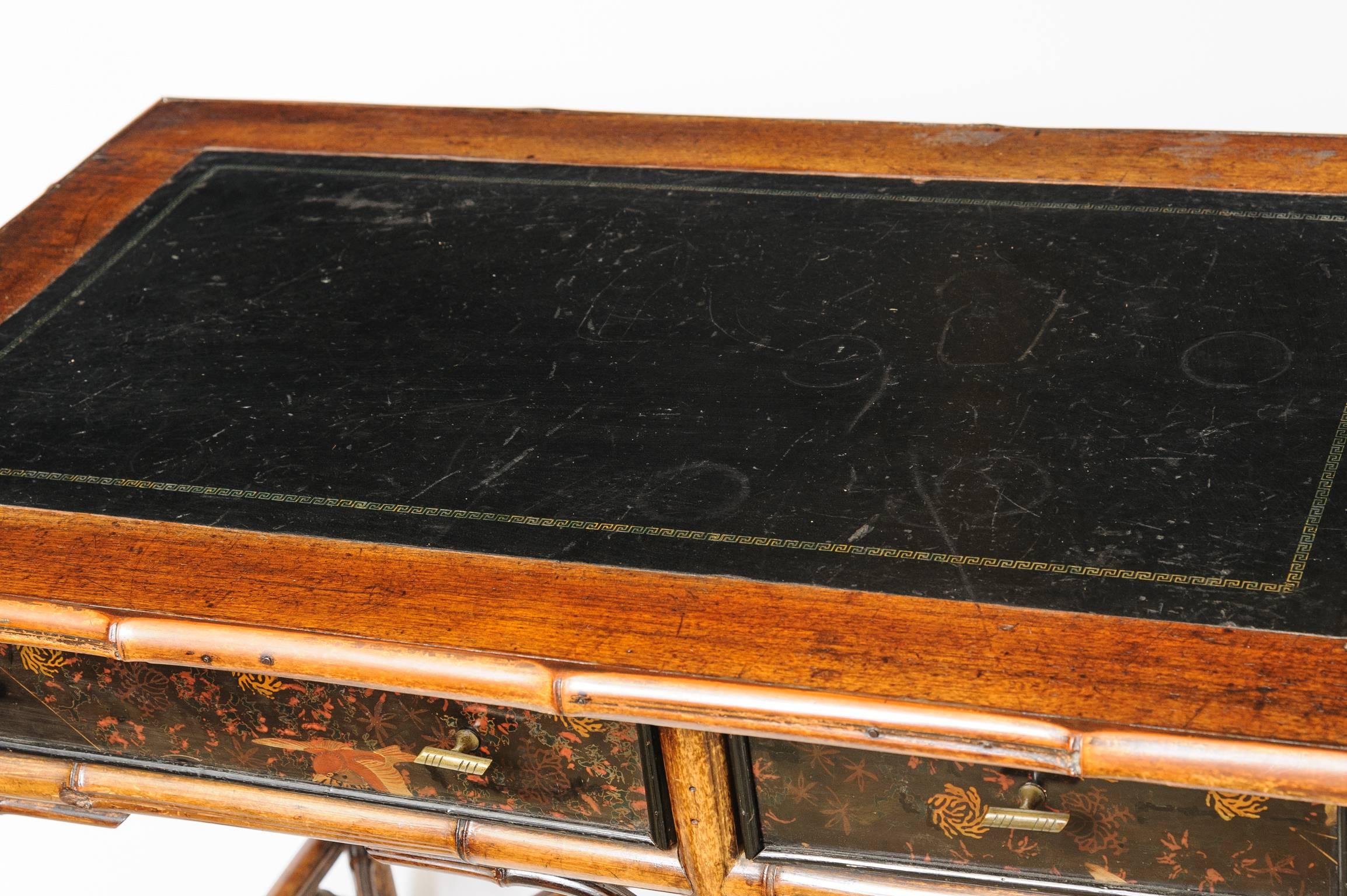 19th century English bamboo desk with three drawers and black leather writing surface decorated with a gold Greek key design.