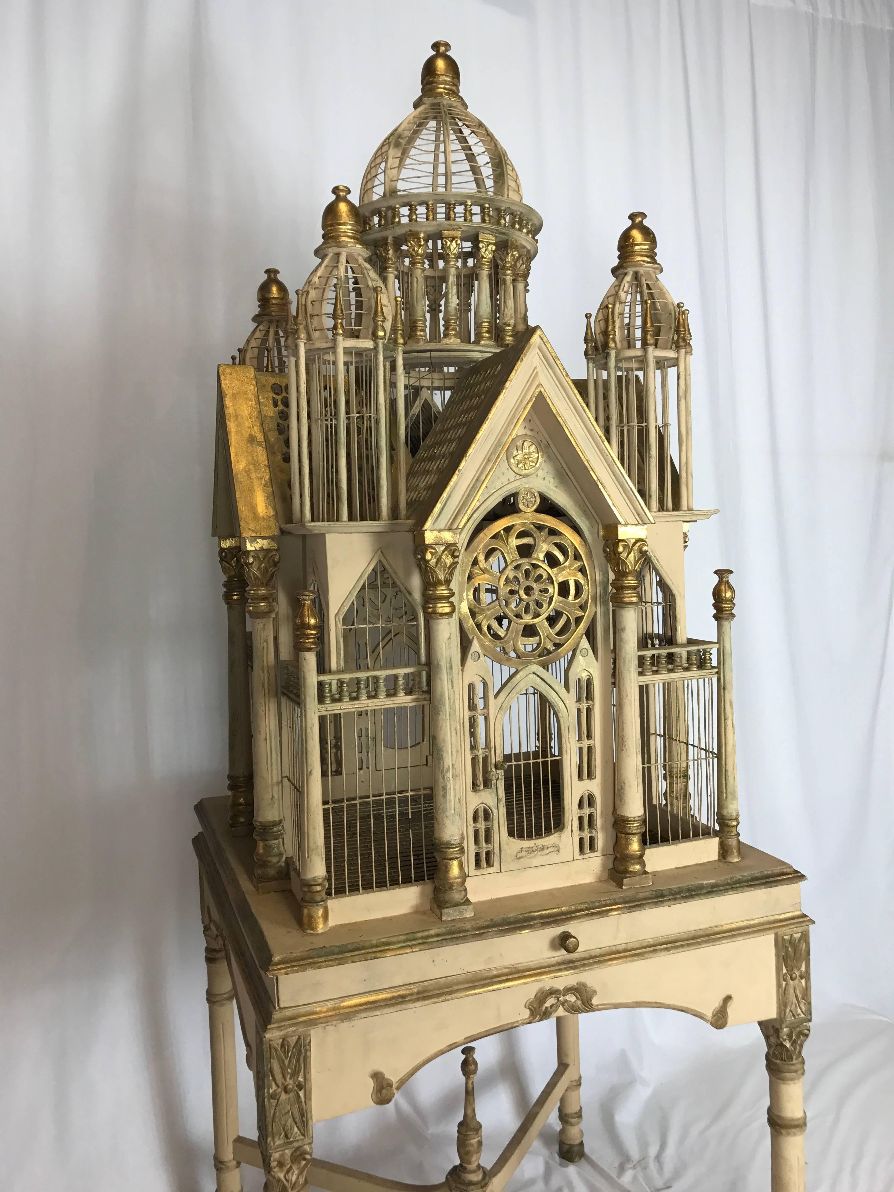 Superb vintage Victorian style cathedral bird cage. This cage come in two part form having the upper cage with center dome and four turrets, paladian style doors and pullout cleaning tray. The base has turned legs with an x-stretcher. Cage is