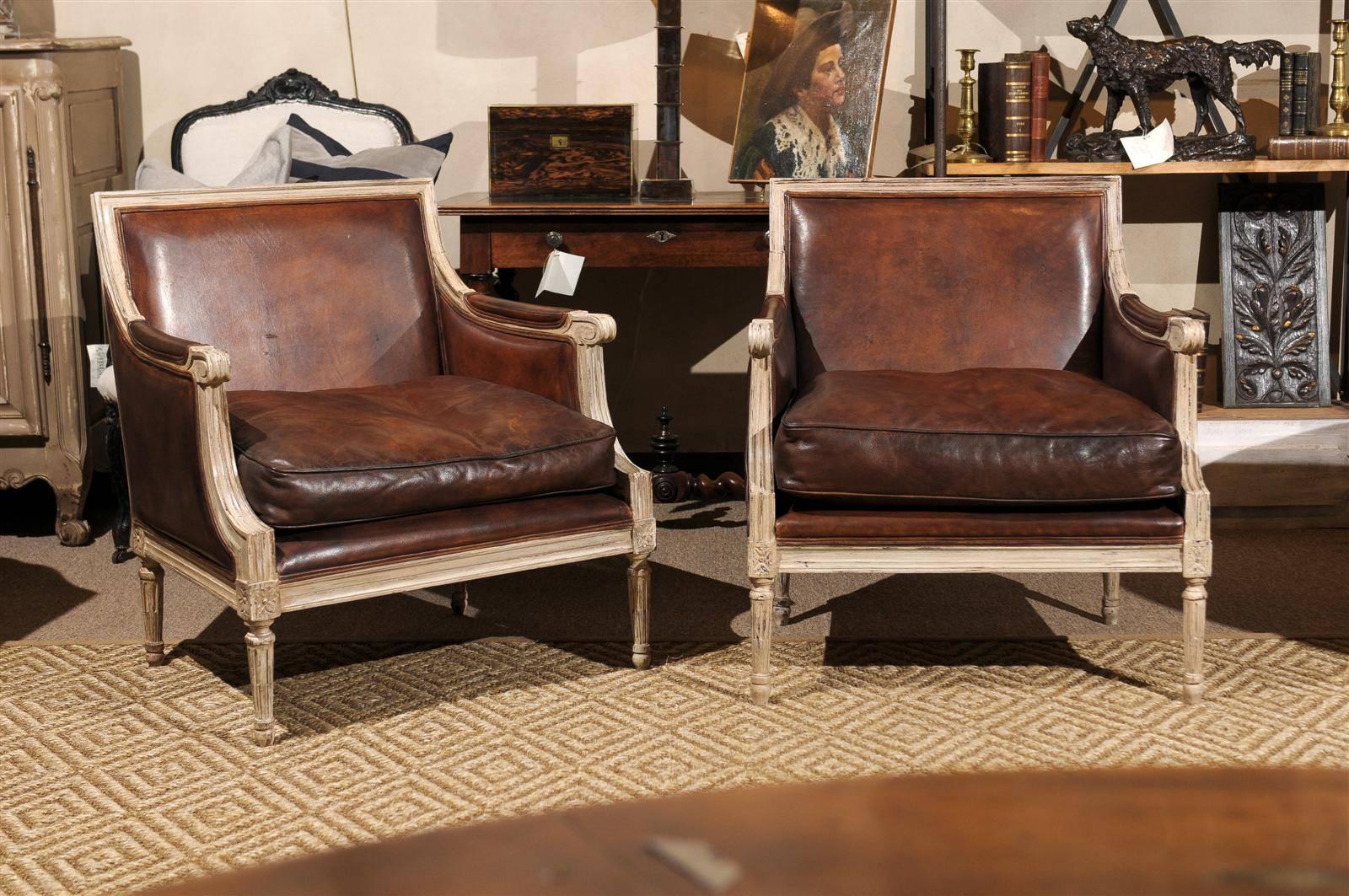 We love the contrast of the dark leather outlined by the light painted frame of these Louis XVI style armchairs. This makes for a very handsome look. The chairs are very comfortable and are a great size, and they have been made with shorter legs for