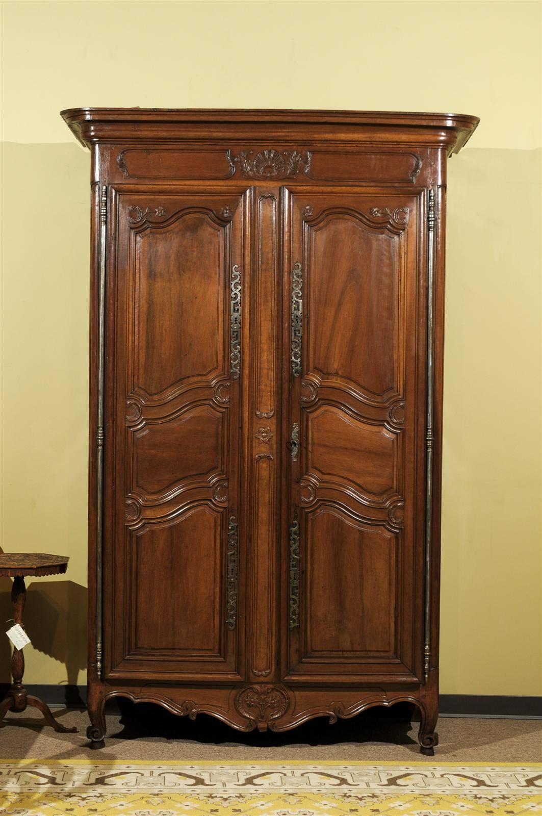 A gorgeous piece of walnut has been created into a stunning armoire. There are lots of details on this piece making it look very rich. Each of the panels are adorned in the corners with tiny flowers and the cornice has a fanned shell surrounded by