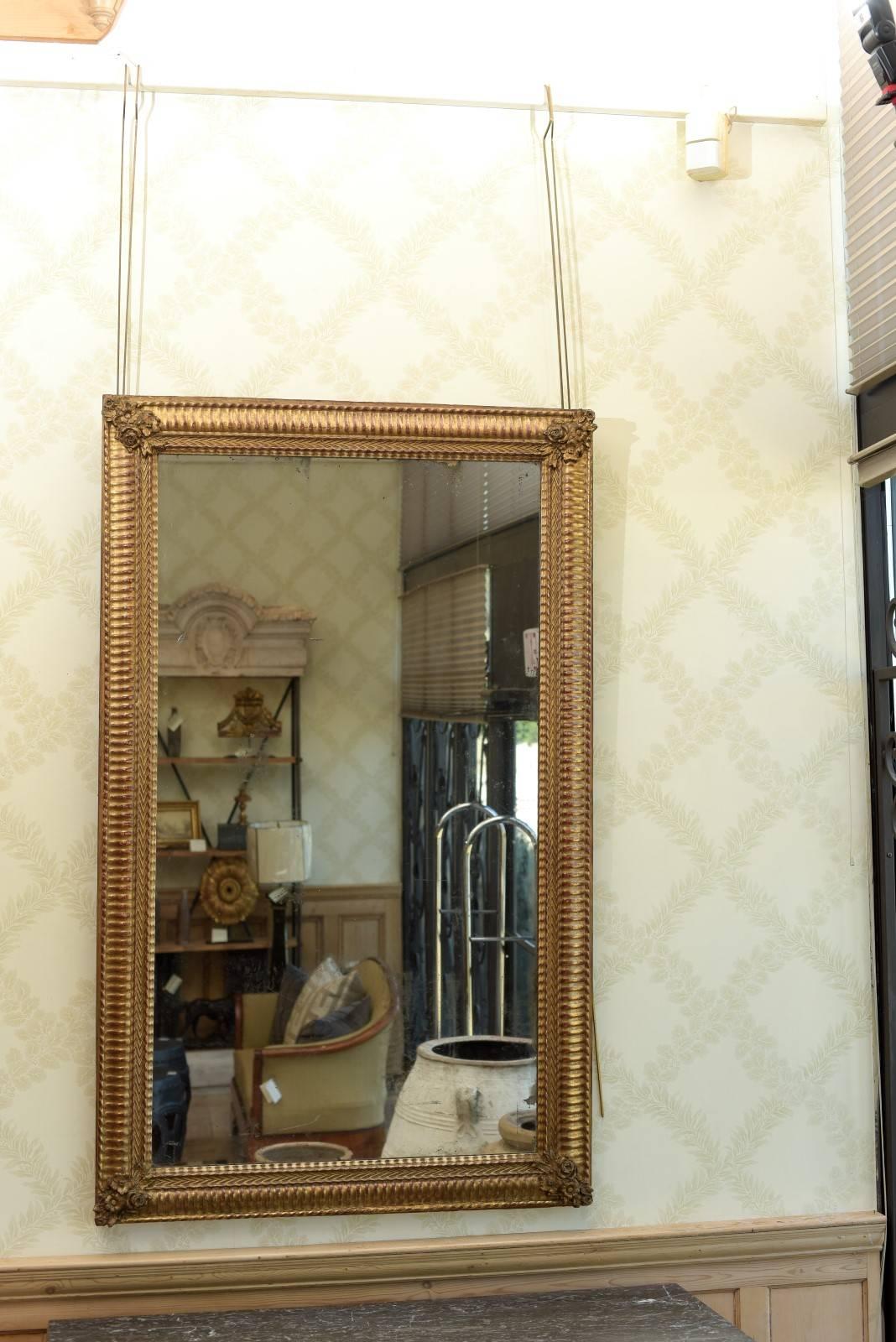 19th century Restauration period gilt mirror, circa 1830.
This is a magnificent mirror from the earlier part of the 19th century with a nicely detailed and carved wood frame.  Although the frame is overall straight lined there is a trio of flowers