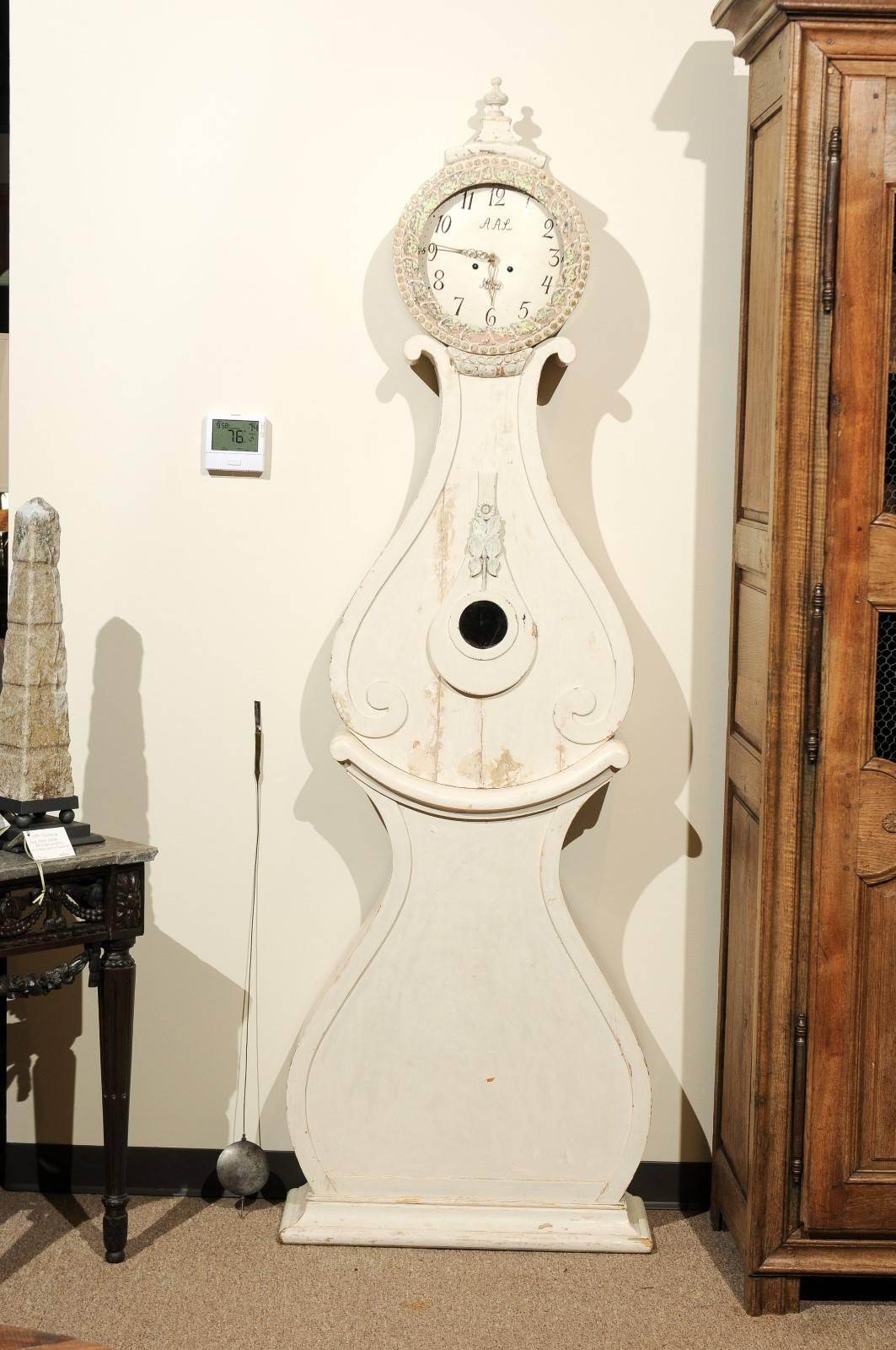 I love the size of this Swedish clock. It commands some room. The clock has the Classic Swedish painted finish of white wash and very simple lines. The designer must have been imaginative because he carved a small sunflower in the middle of the