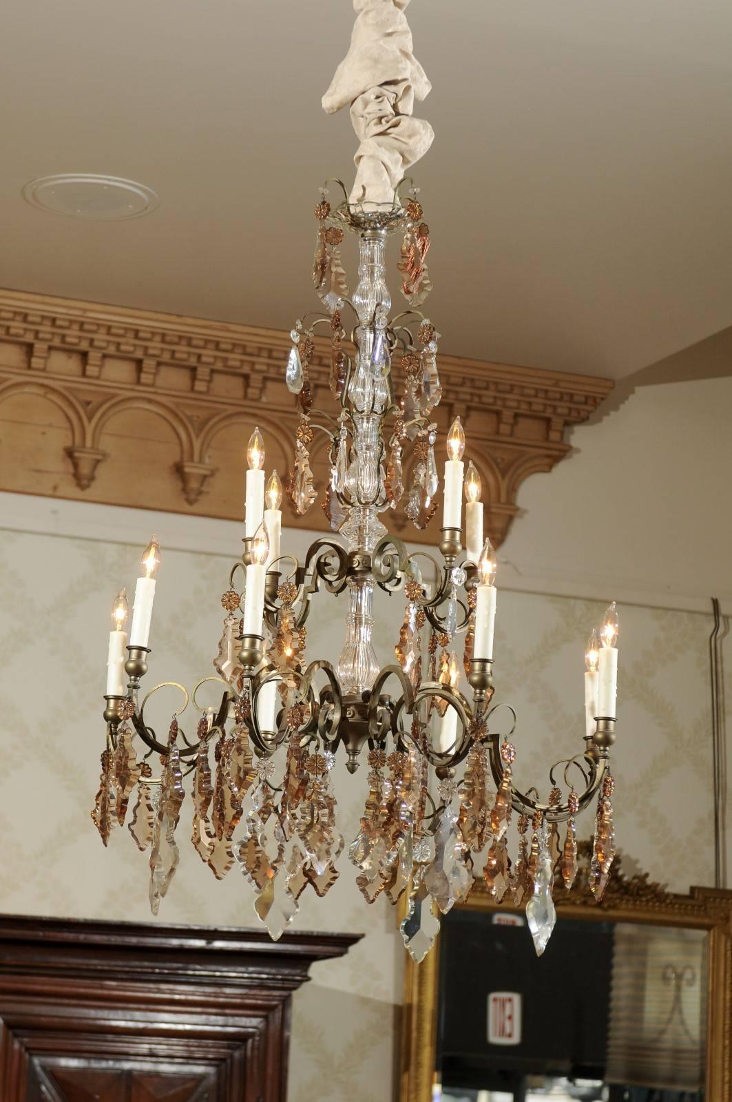 Vintage French bronze and crystal chandelier with 12 arms, circa 1940.
The design of this chandelier consists of five tiers with just crystals on the top three tiers and the 12 lights carry the bottom two tiers. The crystals are alternating colors
