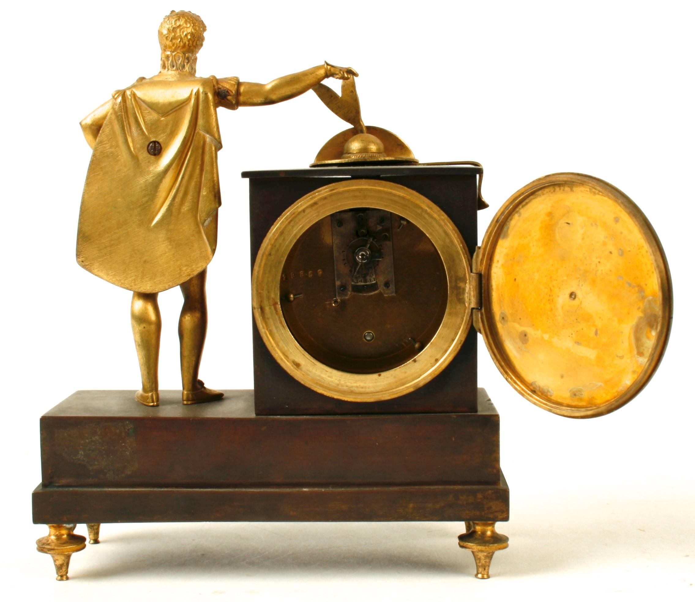 This handsome bronze mantel clock is from the French Empire period with a standing figure placing his feathered hat on top of the clock. The clock’s enameled face is surrounded by an ormolu twisted rope frame. The base is mounted with a tournament