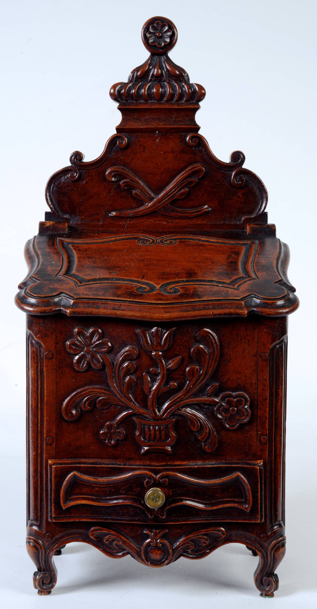 This exceptional French candlebox, c1800, has fine hand-carving and a beautiful patina. It has a candle compartment covered with a hinged slant shaped lid. Below the compartment is a single carved drawer with a brass knob. The body has a carved