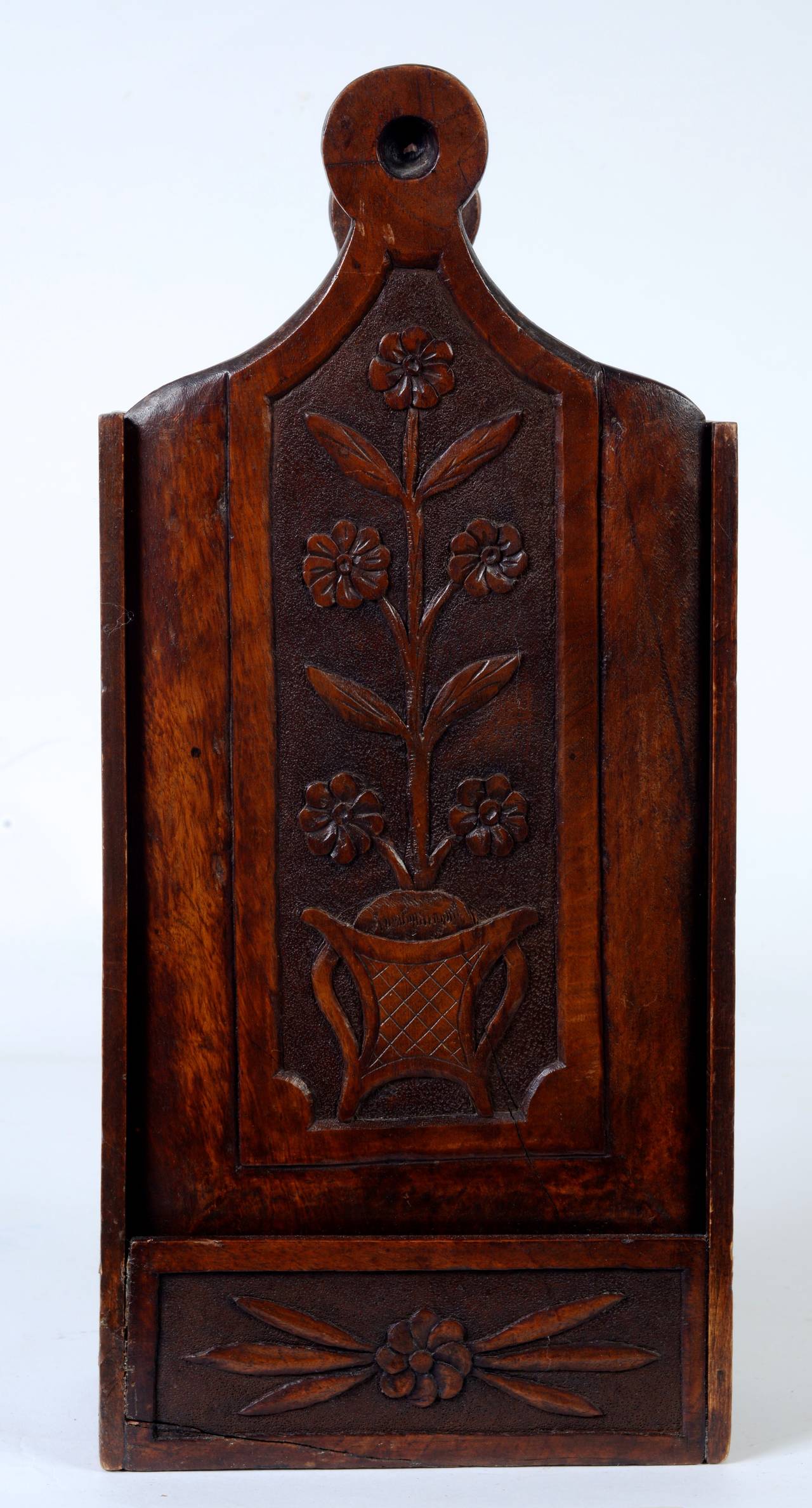 This beautiful French candle box is made of hand-carved walnut. The removable front panel is carved with stylized flowers in a double handled flower pot within a stippled background.
N.P. Trent has been a respected name in antiques for over 30 years