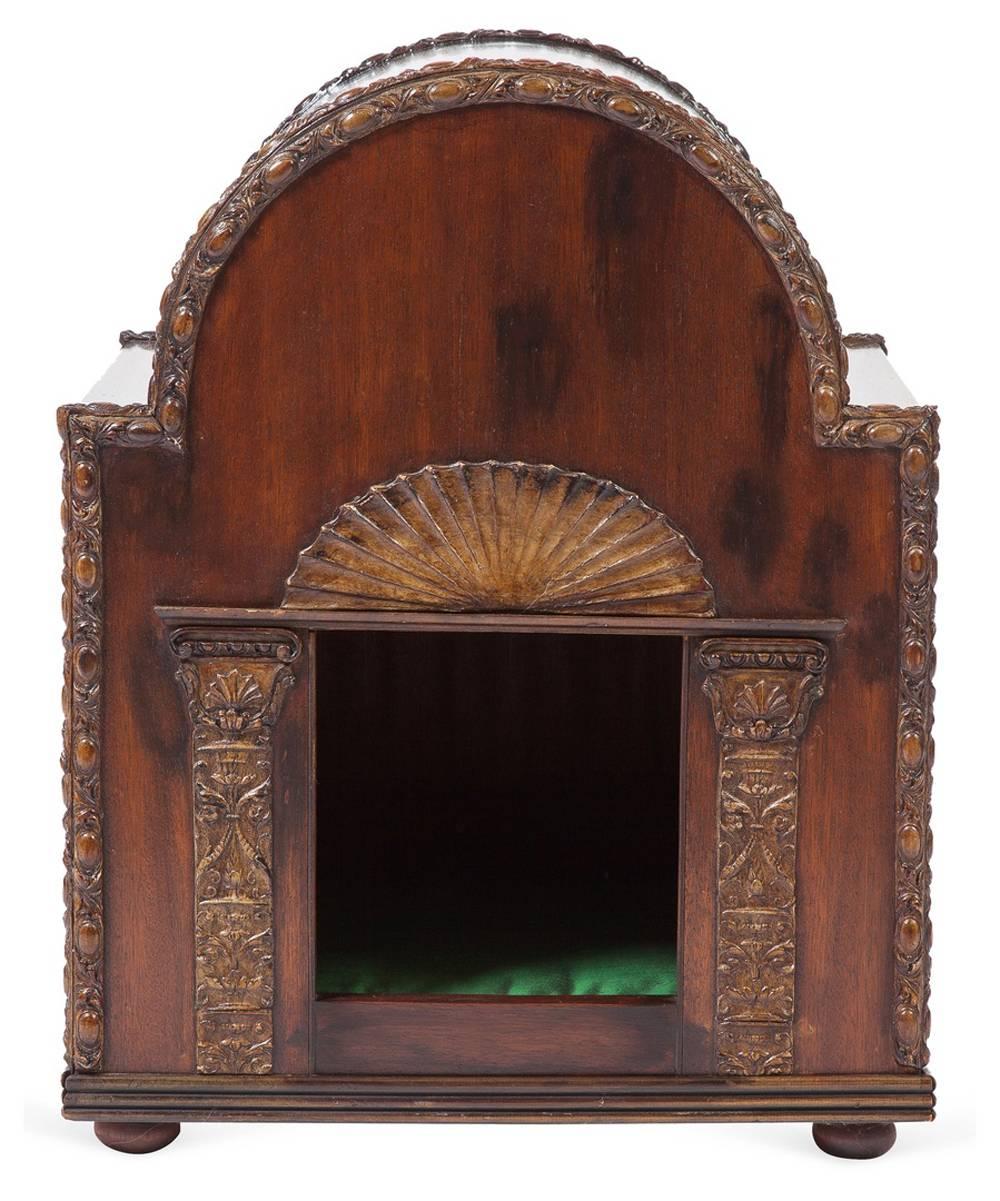 An English Georgian-style domed top mahogany dog house with classical detailing. The piece is trimmed with floral carved bands, the door is flanked with columns and topped with a carved fan. It is lined with a green silk upholstered cushion. It