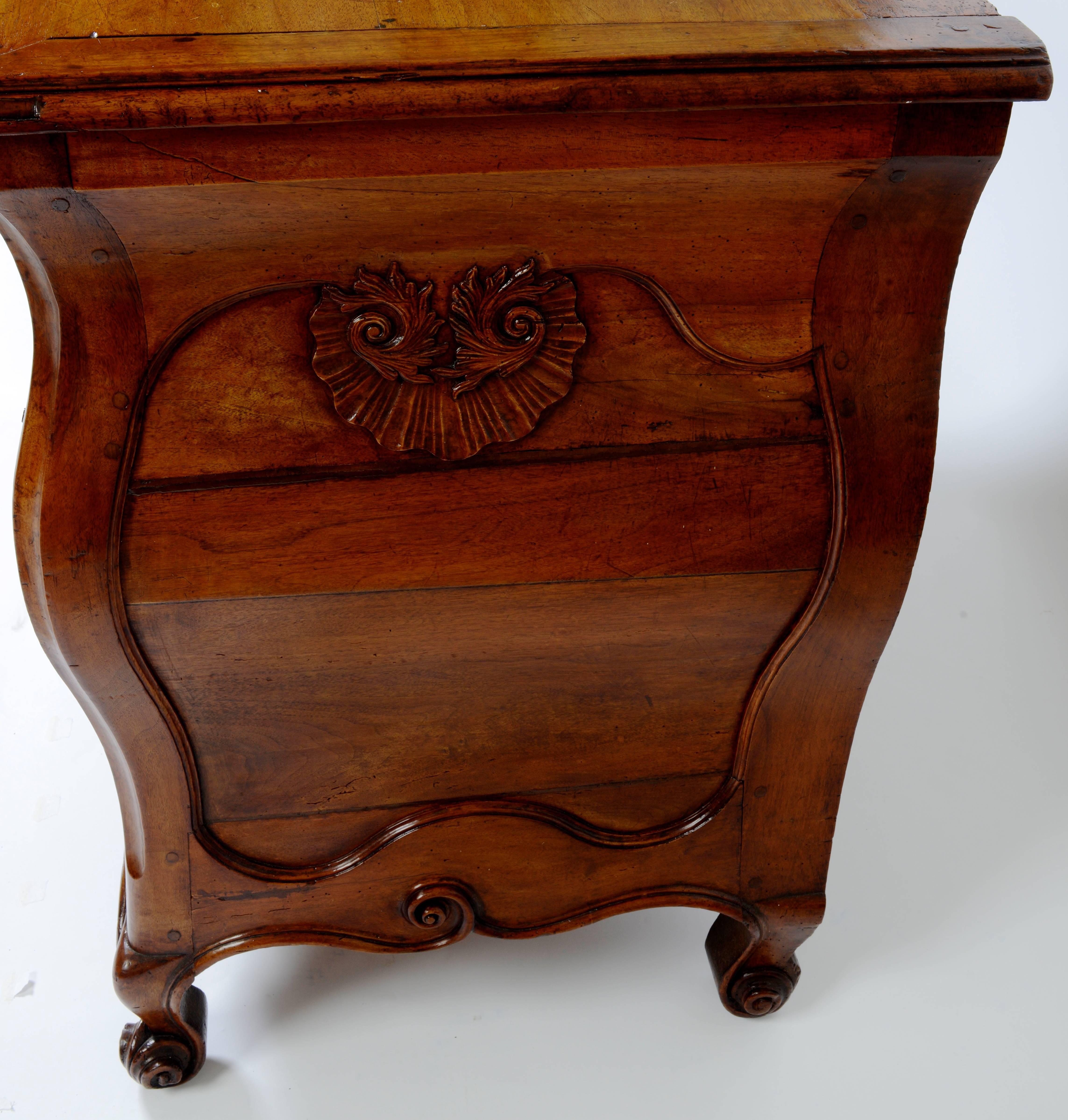 This exceptional walnut bombé commode from the Regence period. It has four beautifully shaped drawers with original rocaille decorated ormolu mounts. The top two drawers have a rare internal locking mechanism with integrated keys and pulls. When the