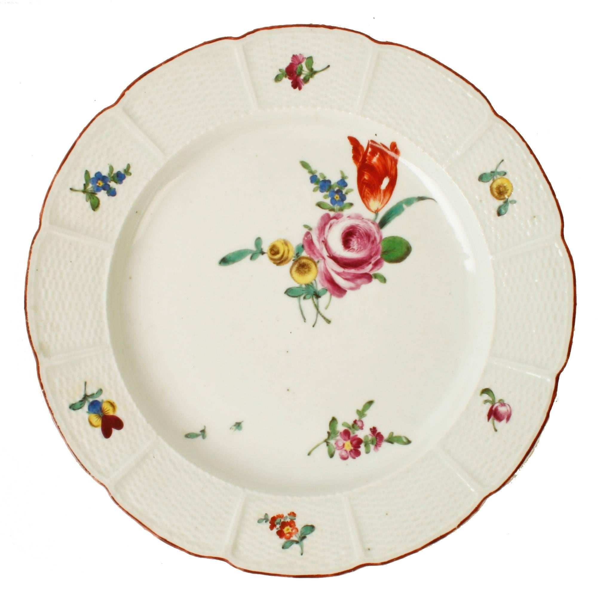 These four Ludwigsburg hand painted porcelain plates are in the scattered flowers pattern with a basket weave rim called the Osier relief decor which is typical of the period. The scalloped edge is trimmed in a reddish brown. They all have